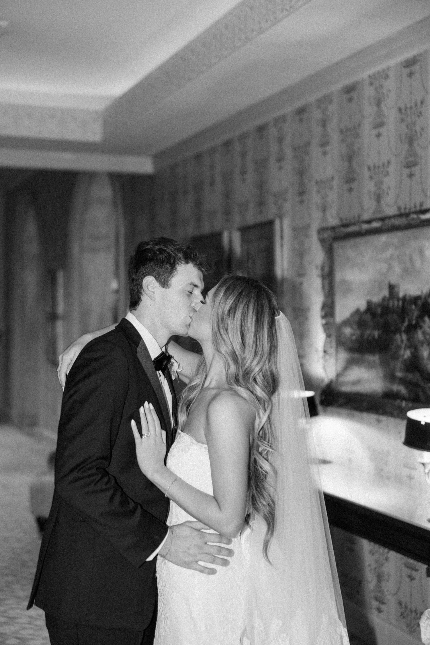 Black and white wedding photos showing tender moments between newlyweds in an elegant indoor setting.