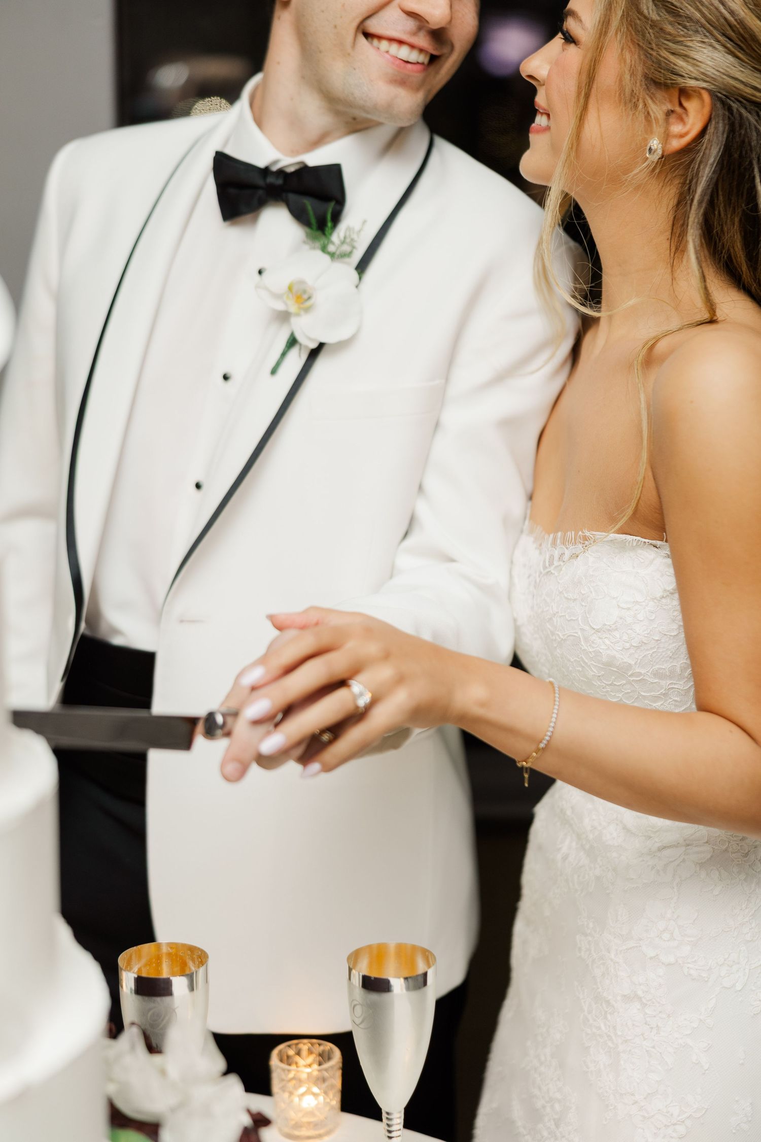 Wedding couple in white attire sharing drinks during their reception celebration.