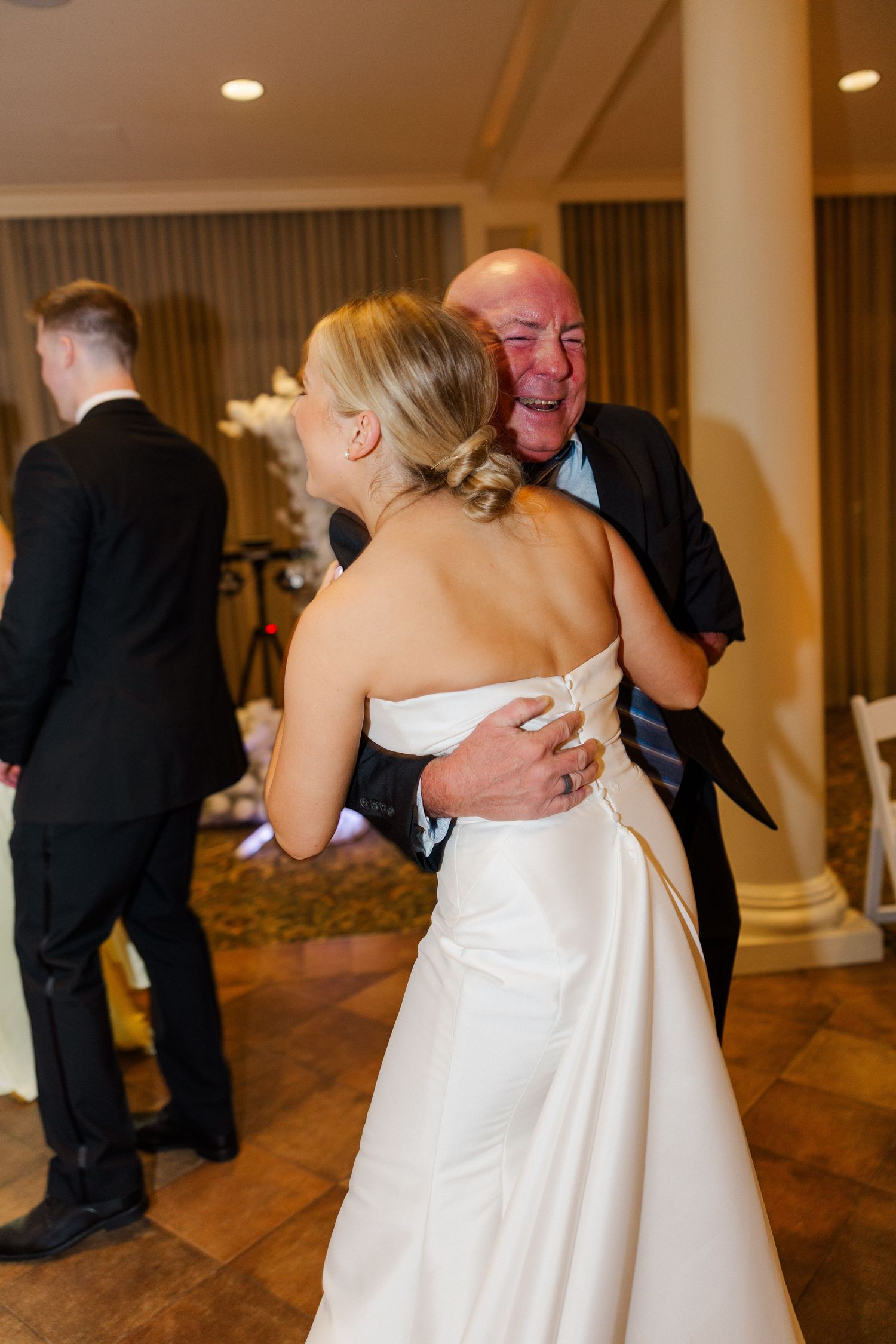 Wedding reception guests dancing and celebrating on a wooden dance floor.