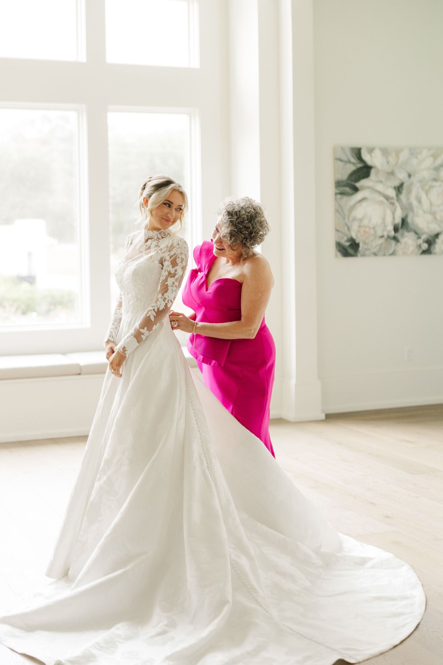A beautiful white wedding gown being admired in a bright sunlit room.