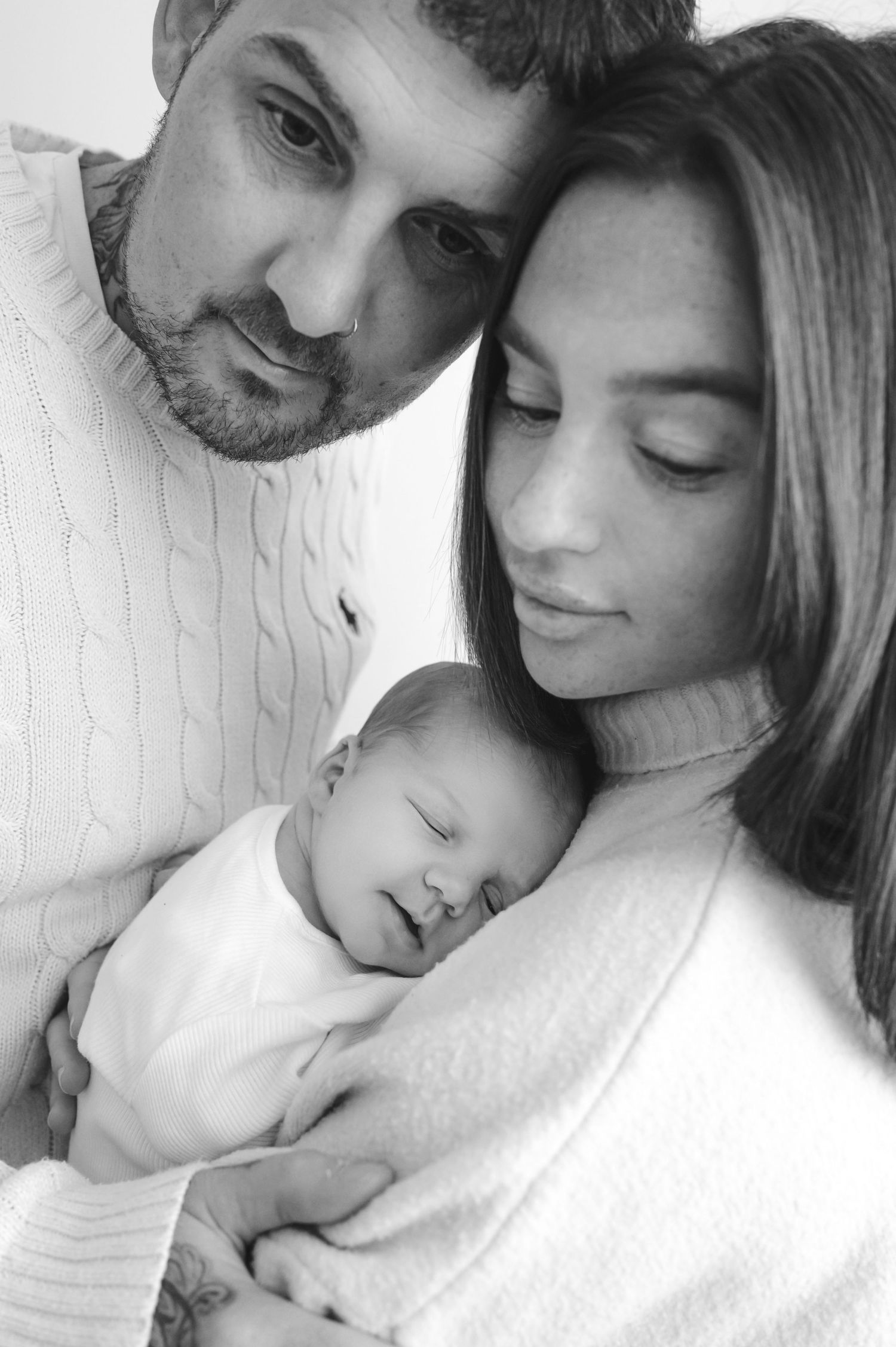 Black and white portrait of parents tenderly holding their sleeping newborn baby, family love photo.