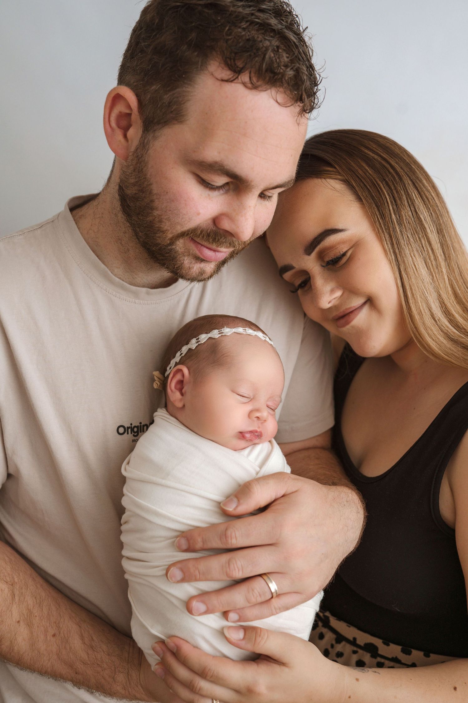 A tender moment between parents and their newborn baby shown in a series of intimate black and white portraits.
