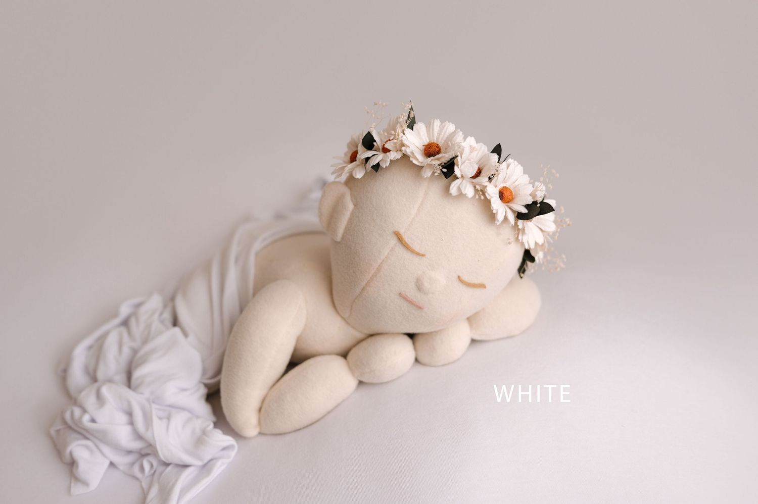 A white ceramic unicorn figurine rests on soft white fabric in a dreamy, minimalist composition.