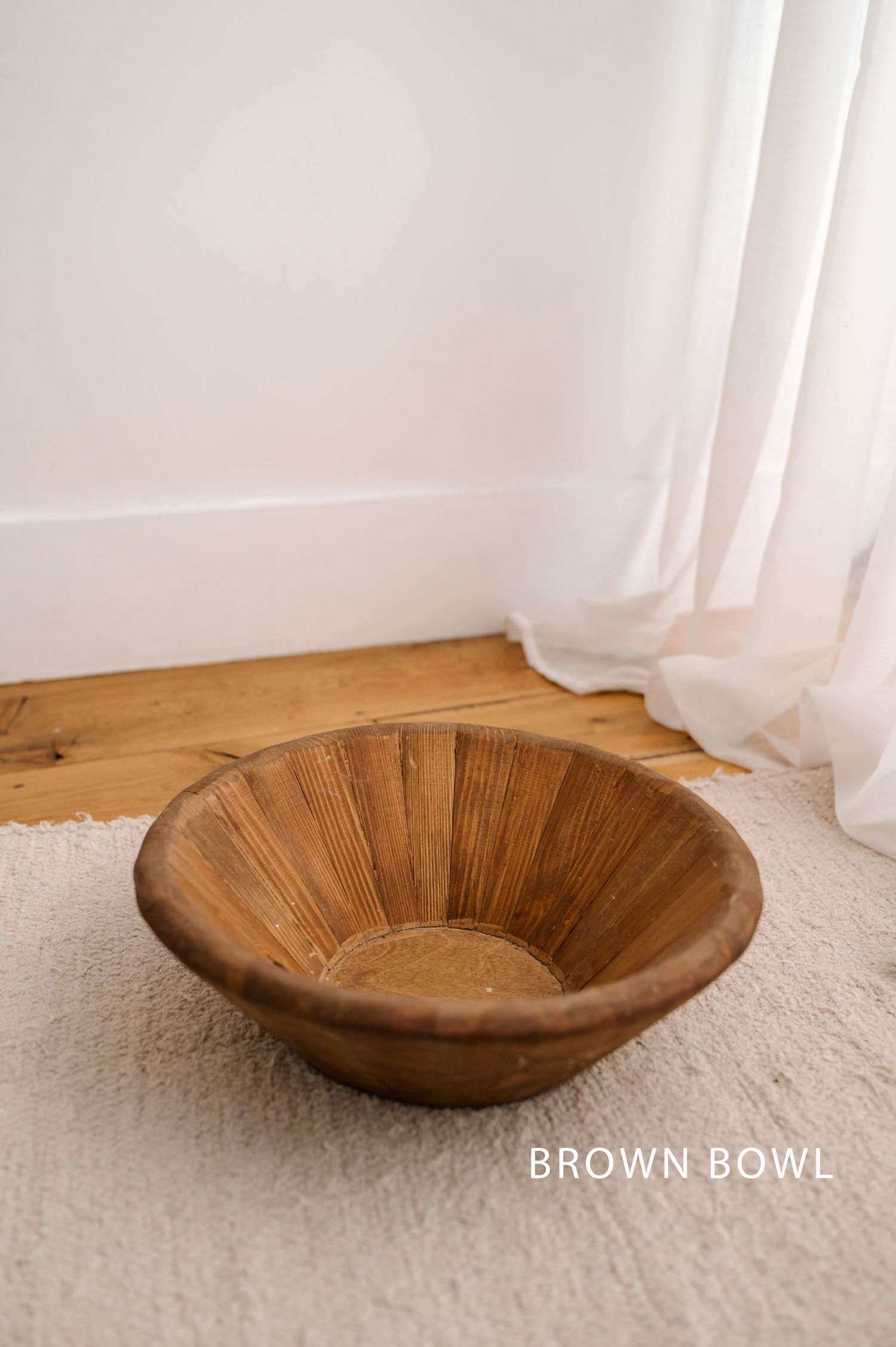 Vintage wooden bowl with ribbed texture photographed from different angles on white carpet against light background.