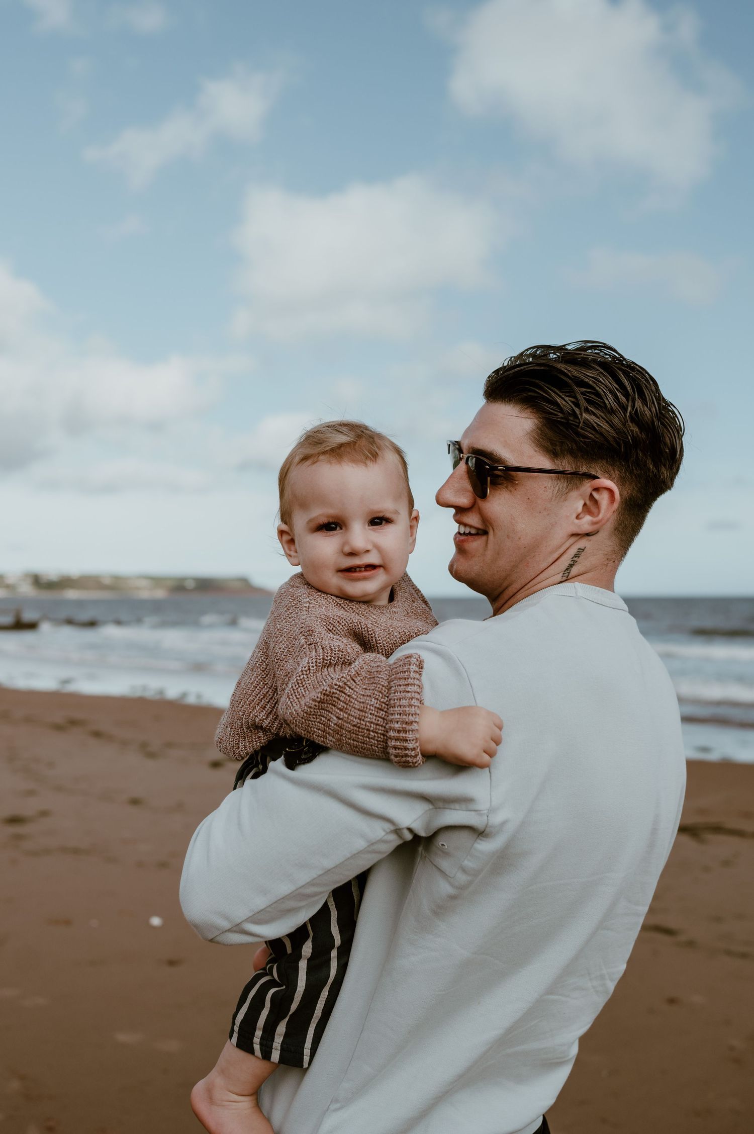 A parent and child share tender moments together while playing on a cloudy beach by the ocean.