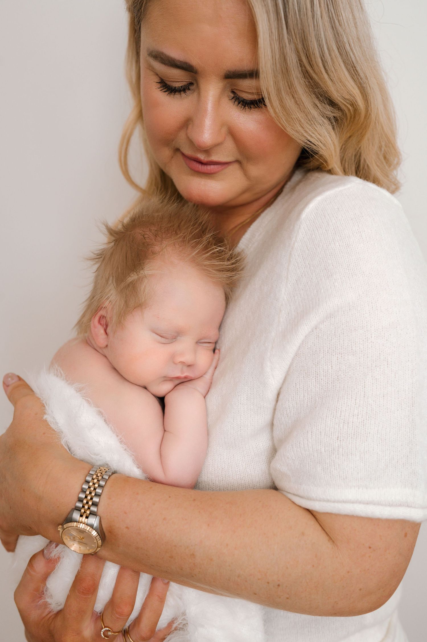 A tender moment captured as a sleeping baby rests peacefully against a white-clad shoulder.
