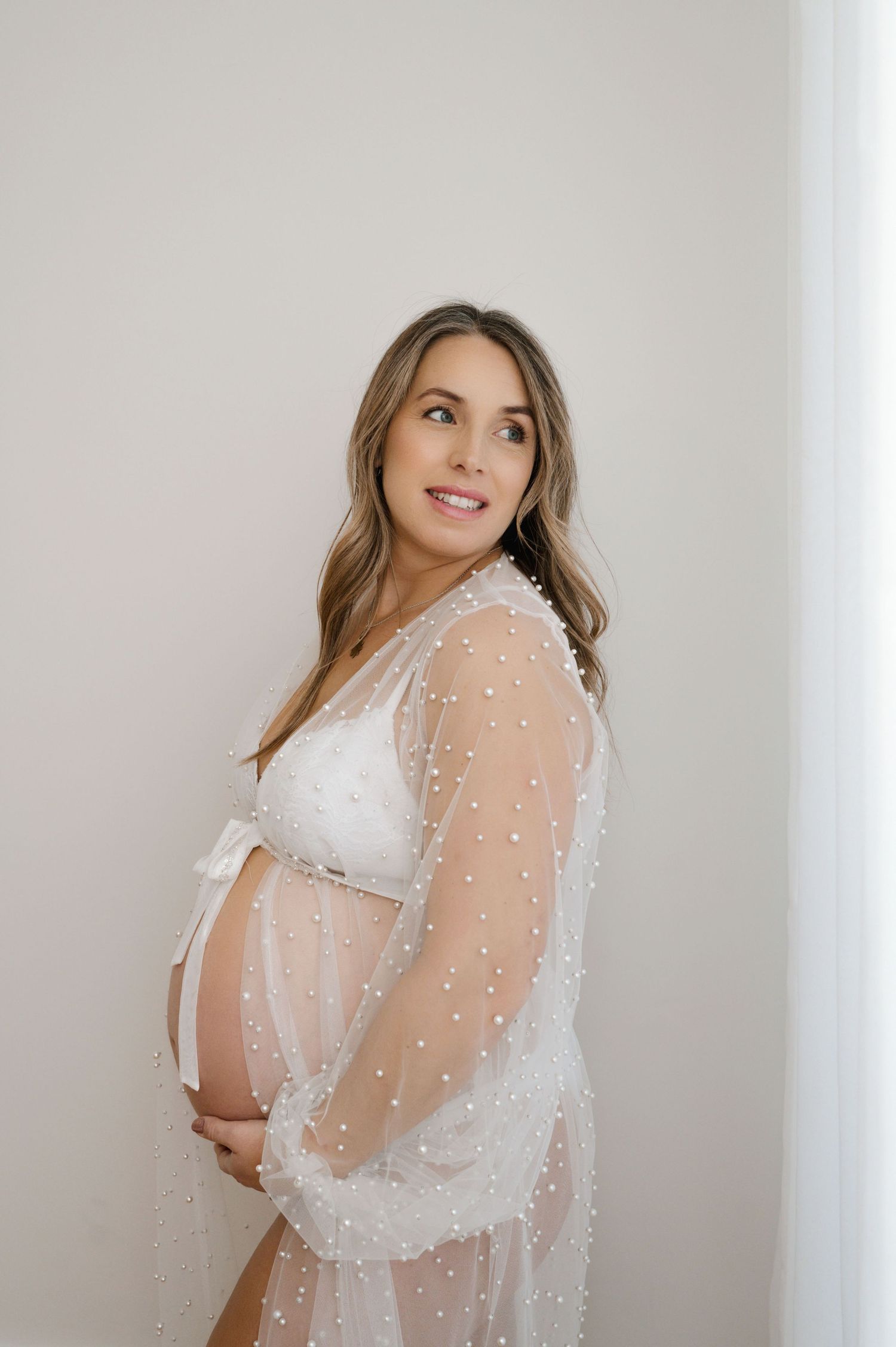 A series of ethereal bridal portraits featuring a sheer pearl-embellished cape against a minimalist white background.