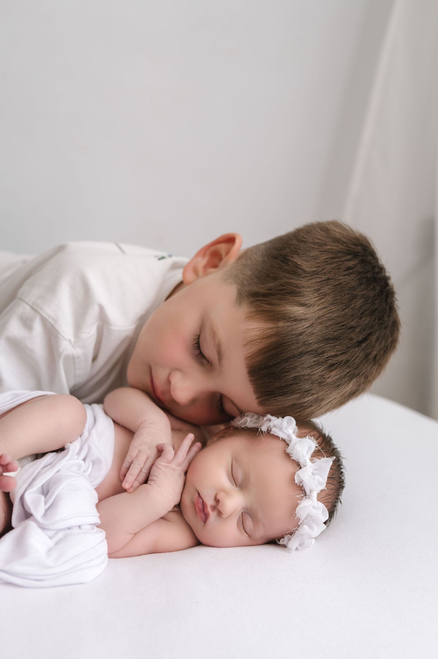 A series of tender sleeping poses captured in white tones showing a gentle moment of rest and connection.