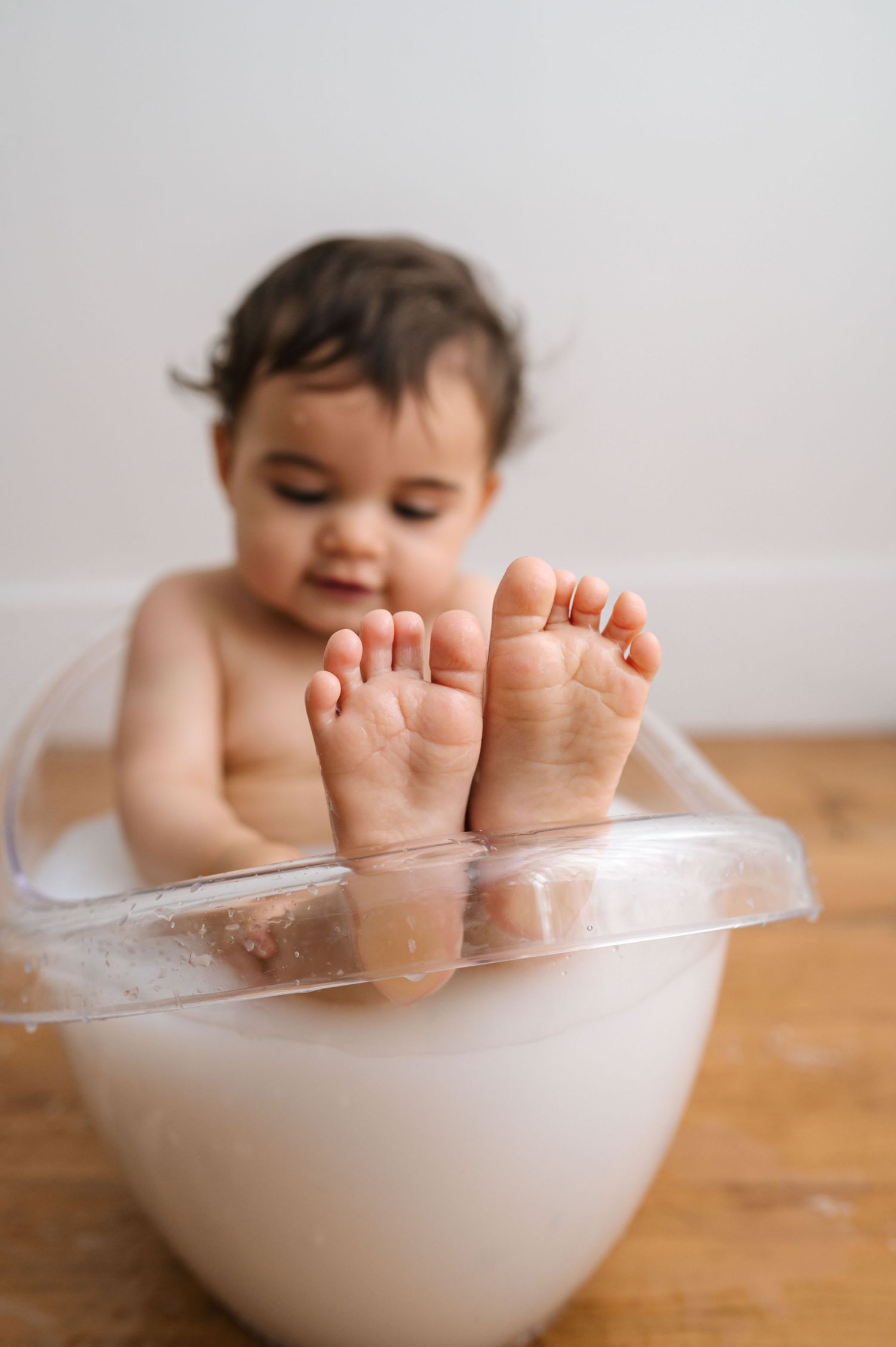 Small feet peek out from a white bowl on a wooden surface in a series of connected photos.