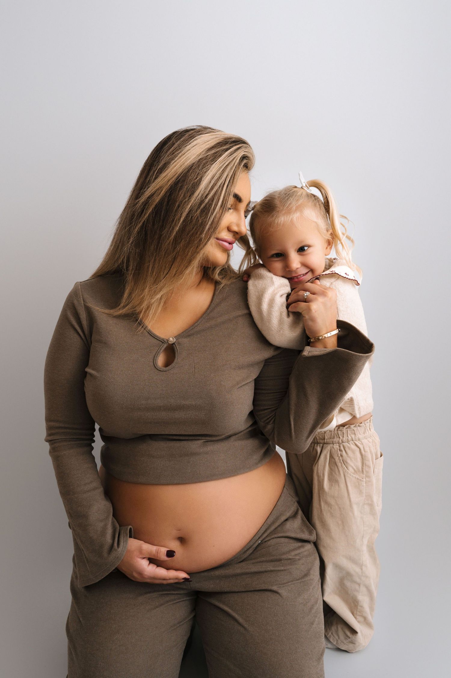 A series of maternity photos showing a growing baby bump in brown clothing against a light background.