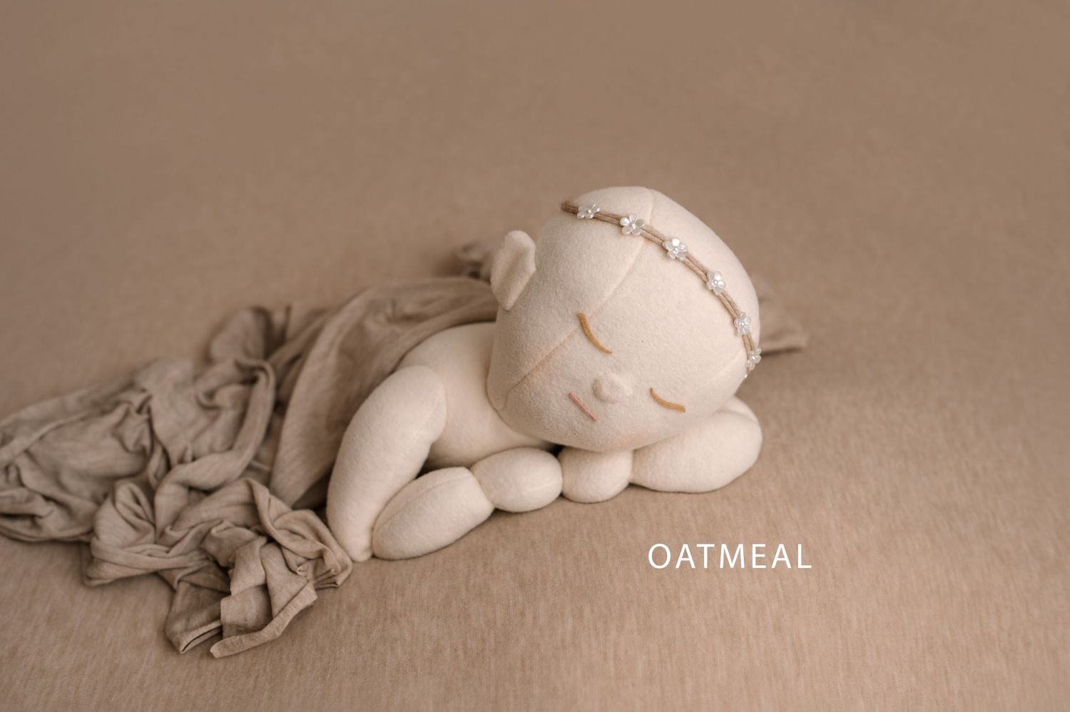 A sleeping white puppy curled up on a beige textured background with soft lighting.