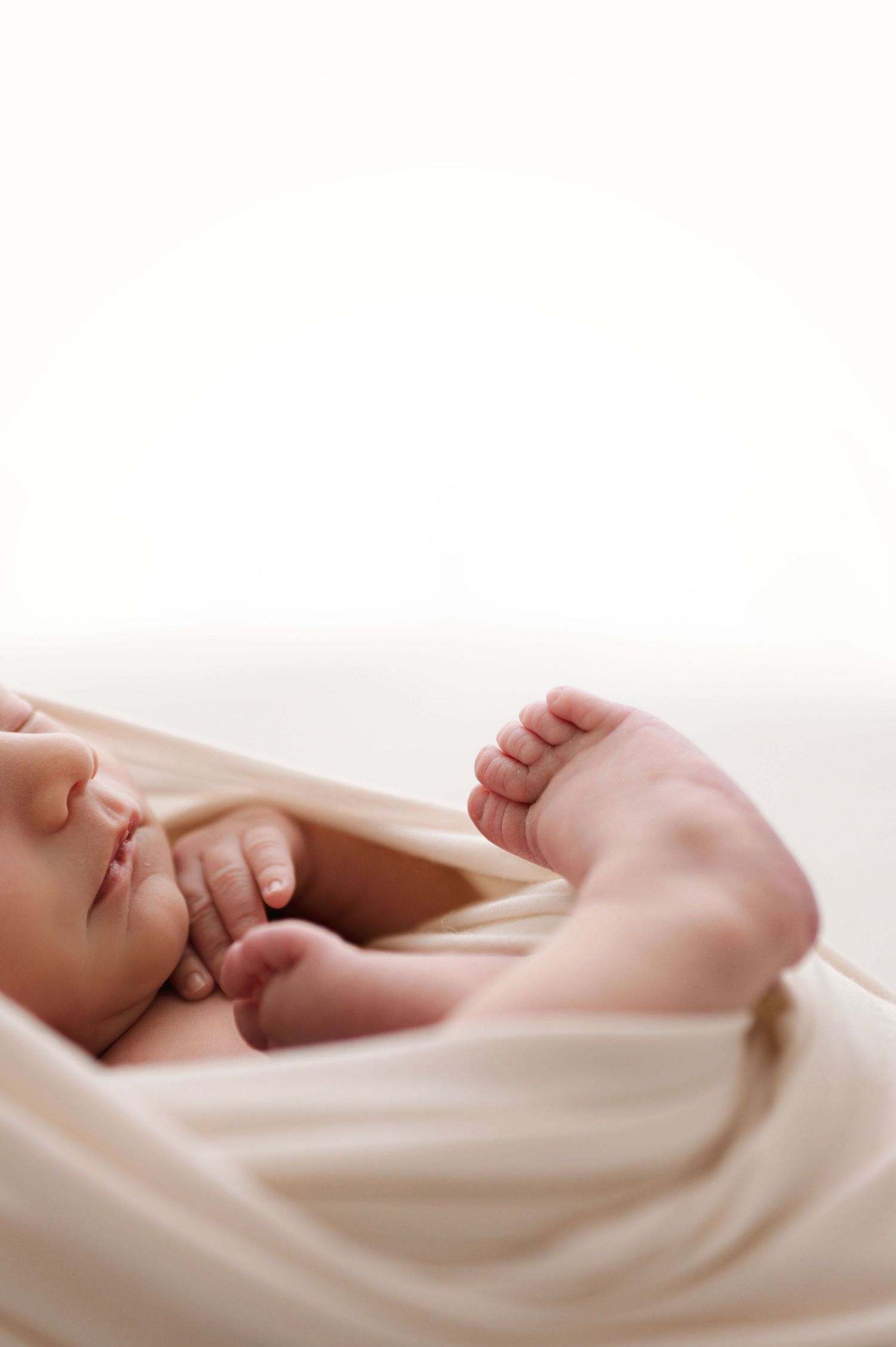 Close-up view of tiny newborn baby feet wrapped in soft cream colored blanket showing through multiple frames.