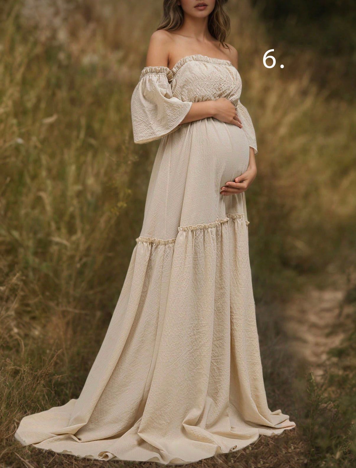 A flowing cream-colored maternity dress with bell sleeves photographed in a natural outdoor setting at sunset.