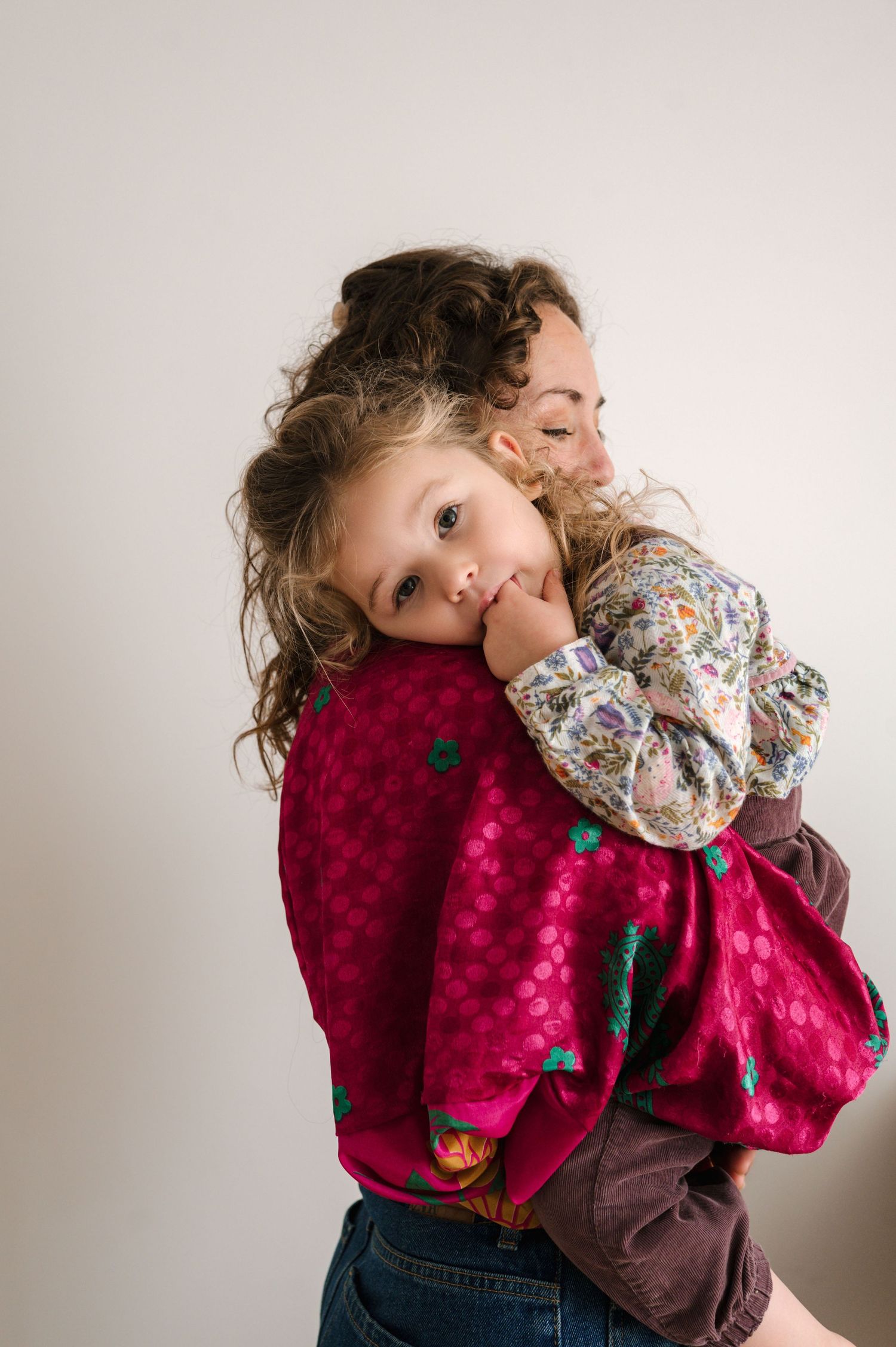 A sequence of photos showing a child in a pink velvet dress hugging and playing with a stuffed toy against a white wall.