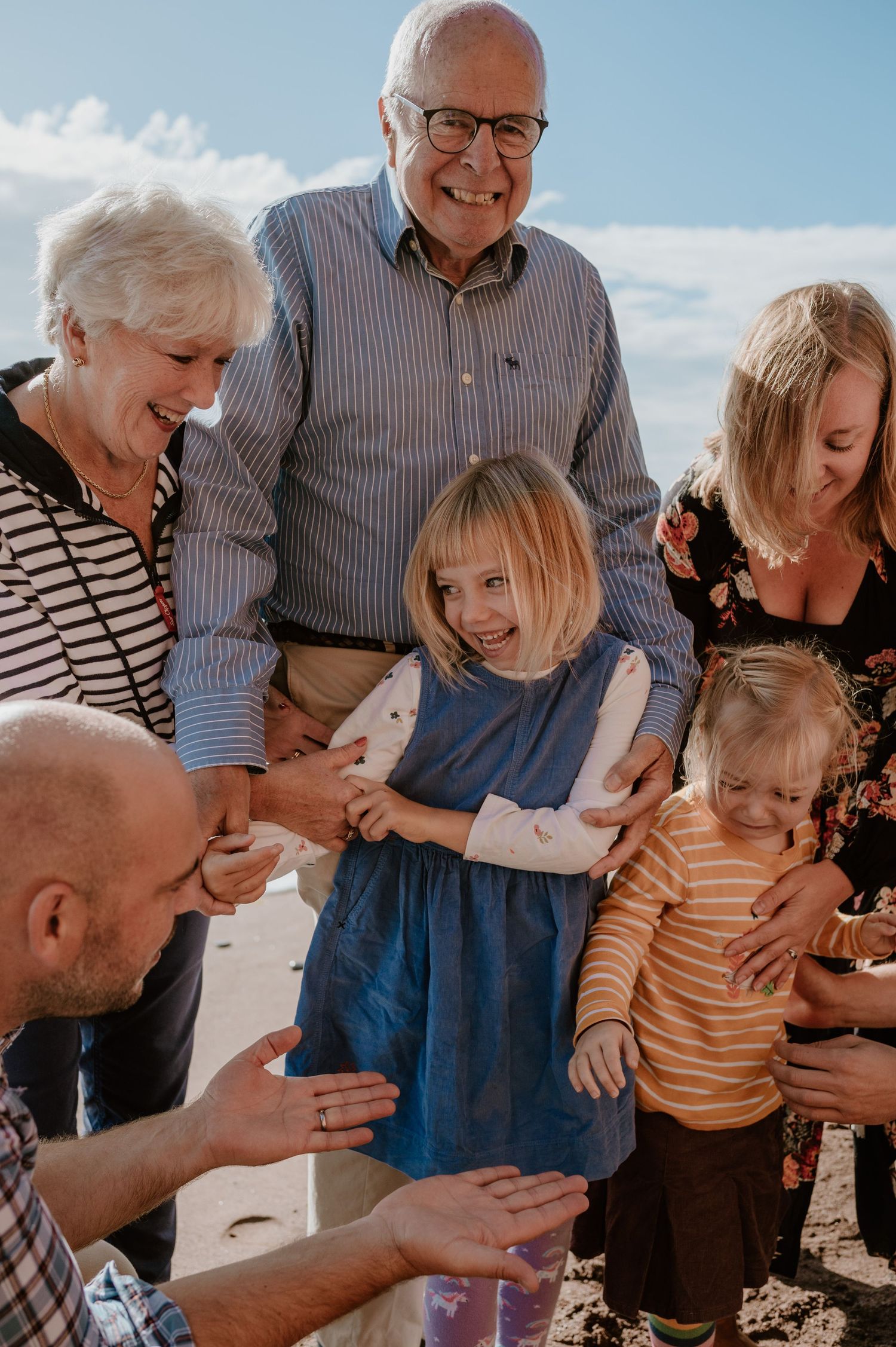 A multi-generational family shares joyful moments together outdoors on a sunny day.