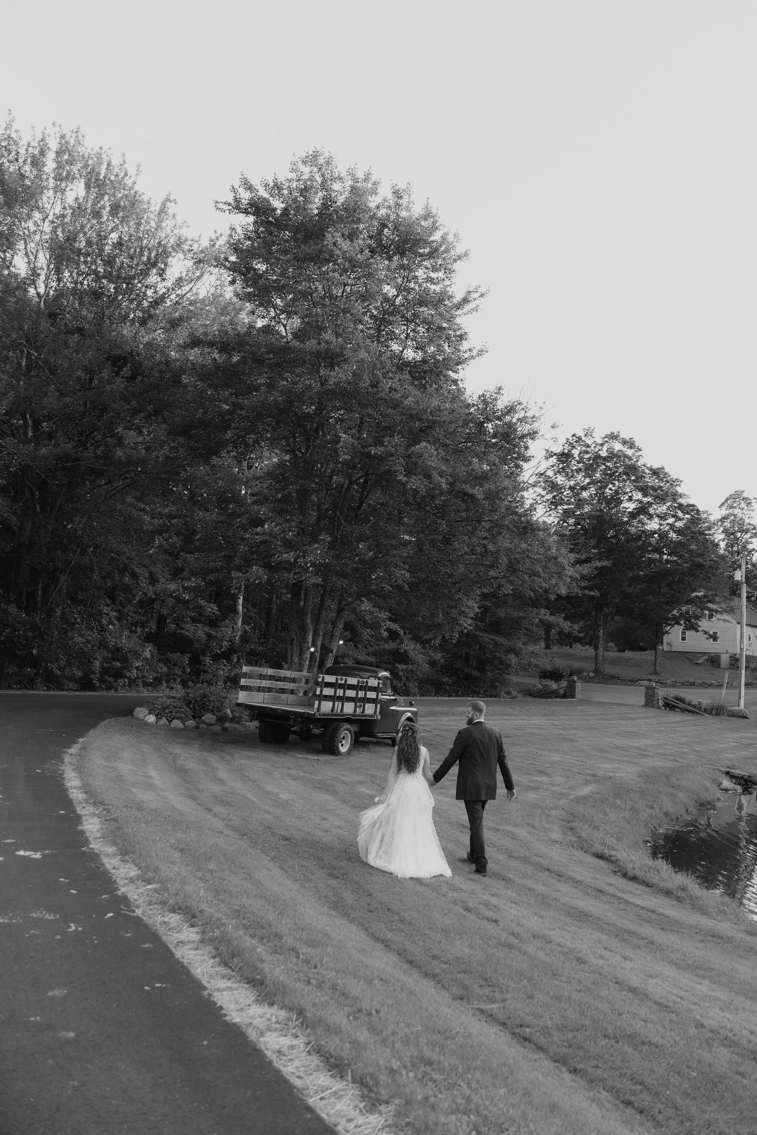 A black and white panoramic sequence showing a couple walking across a grassy hillside at their outdoor wedding celebration.