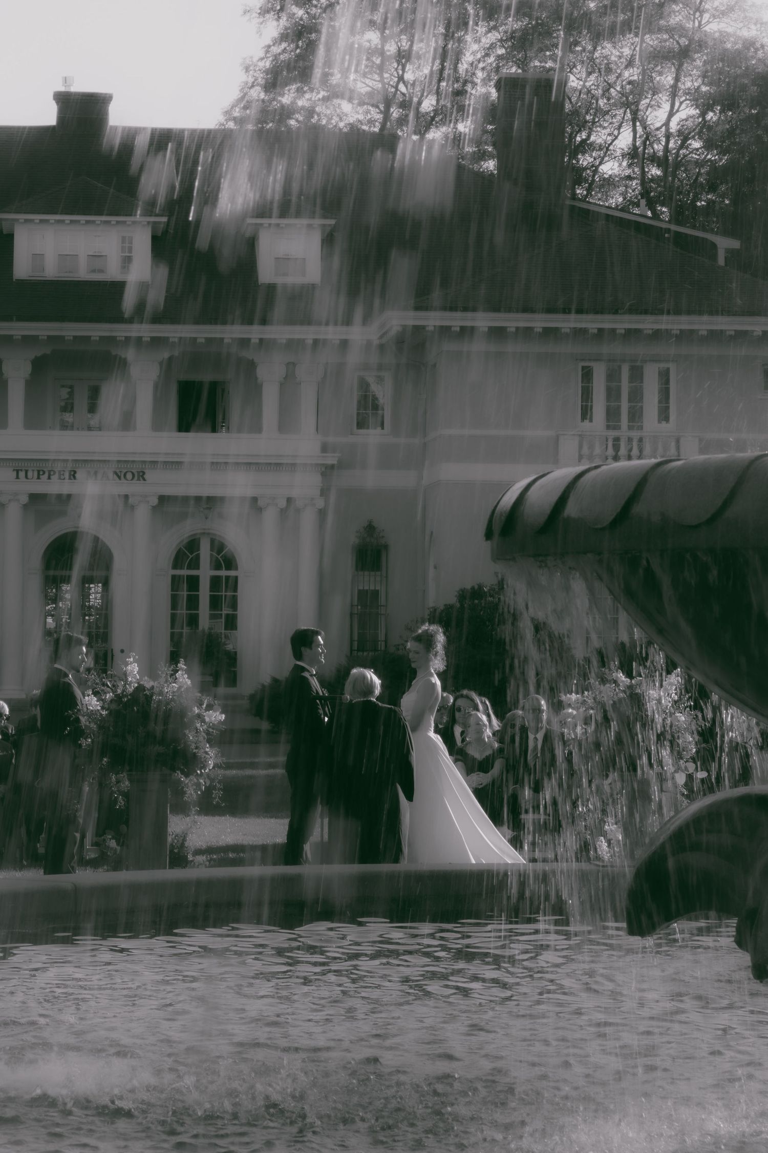 Architectural view of a historic building with arched windows and fountains shot in black and white photography.