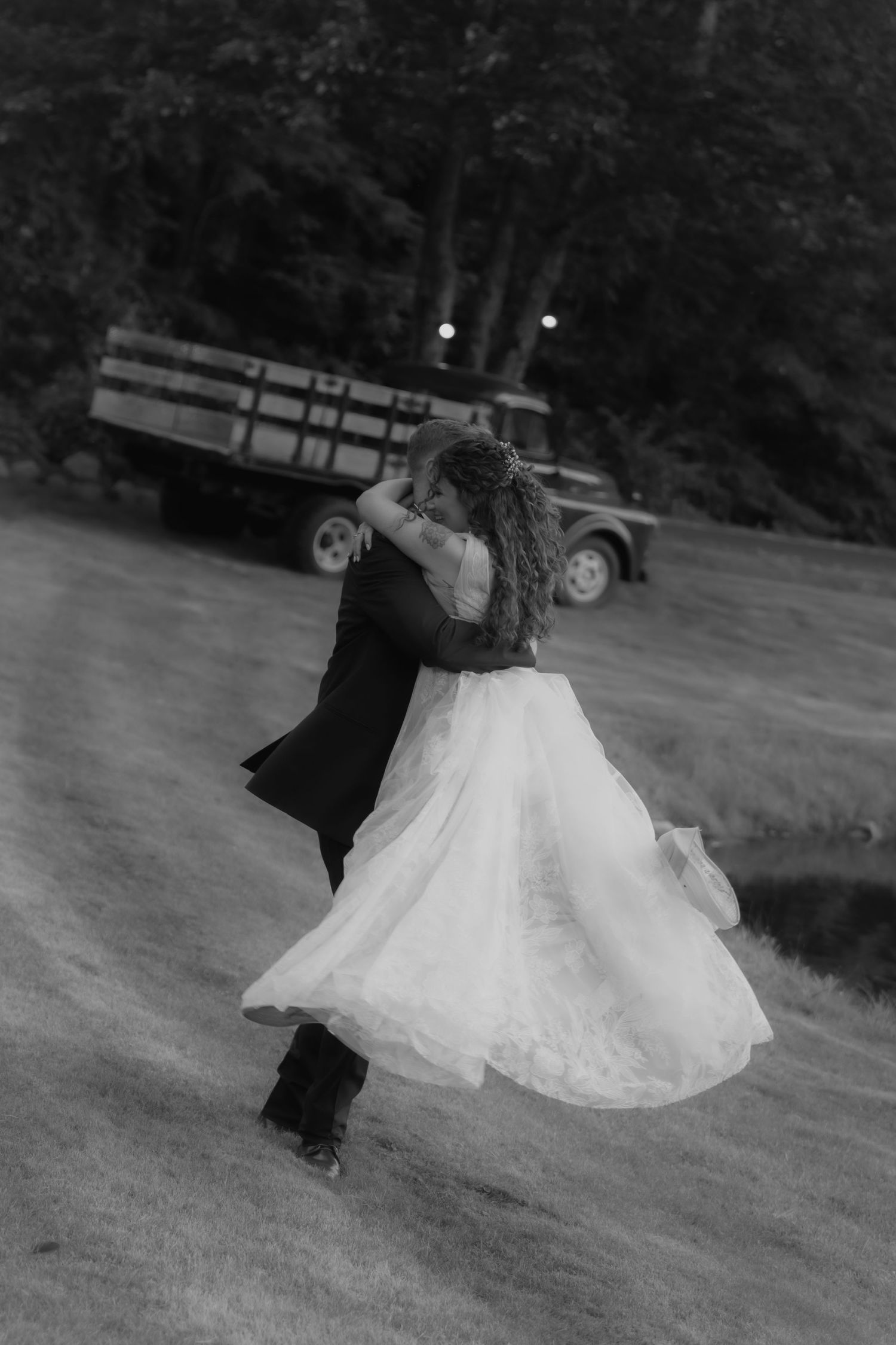 A couple dances together outdoors, with the bride's white ballgown dress twirling gracefully in black and white photography.