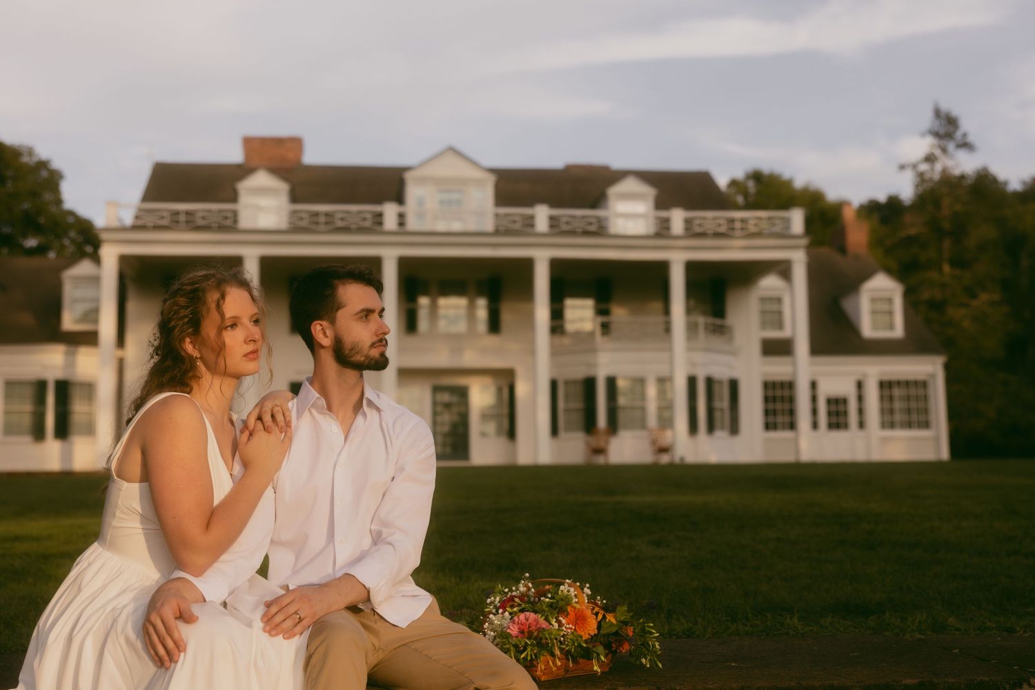 Couple celebrates their wedding day in front of a classic white mansion with elegant colonial architecture.