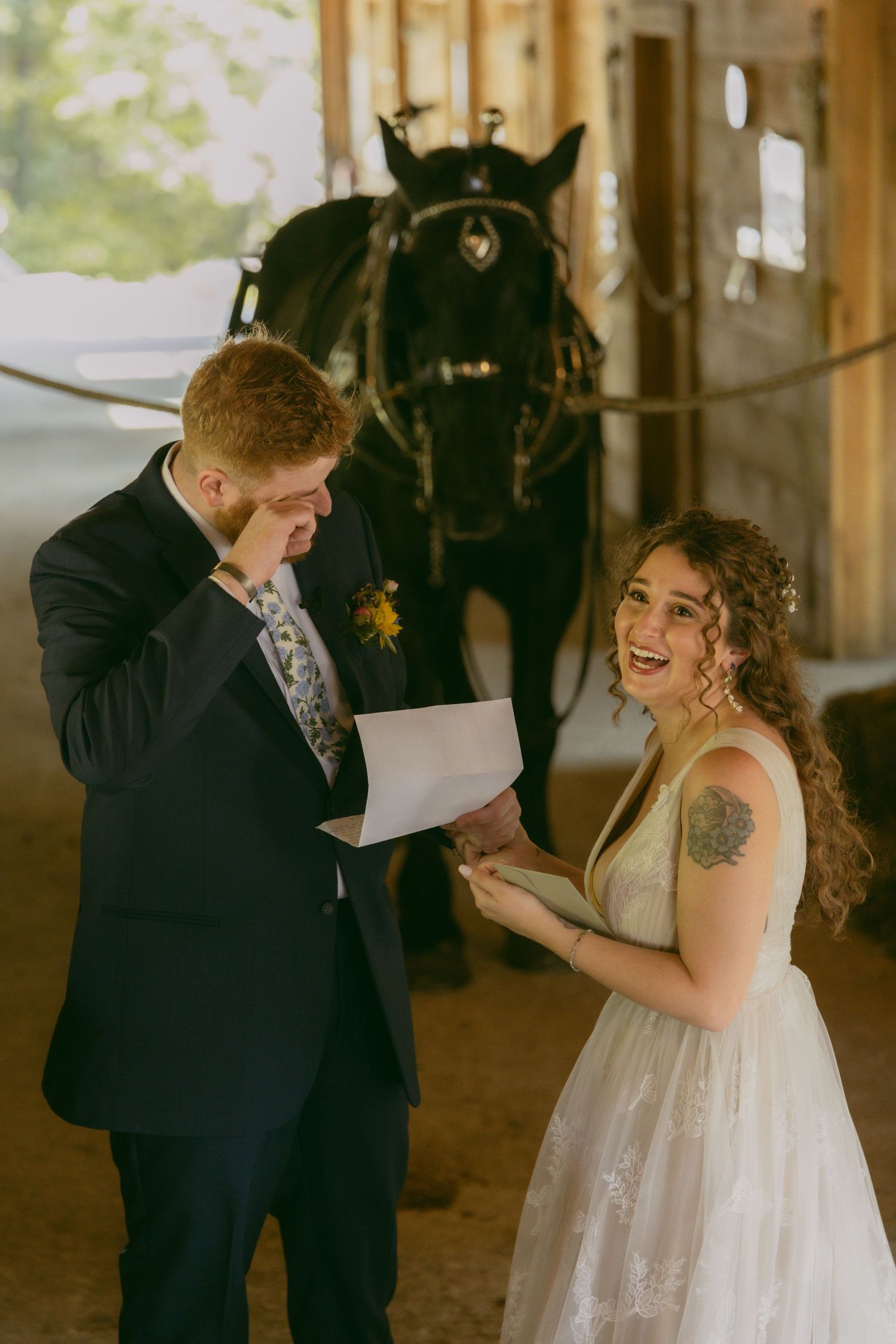 An emotional first look moment between a couple at their rustic barn wedding with a black horse in the background.