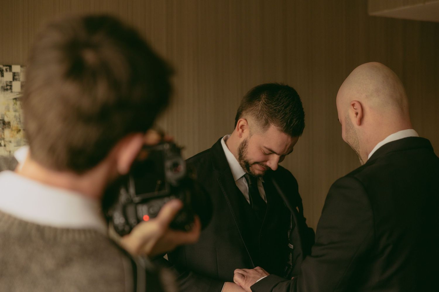 Wedding guests bow their heads in prayer during an intimate ceremony at an indoor venue.