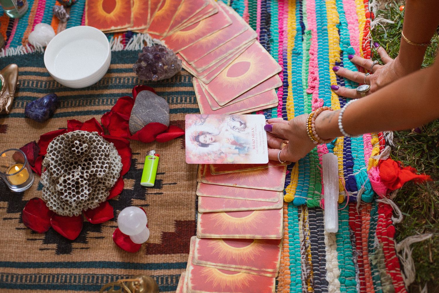 Red cards scattered on a colorful lanyard-covered wooden table during a casual card game with multiple players.