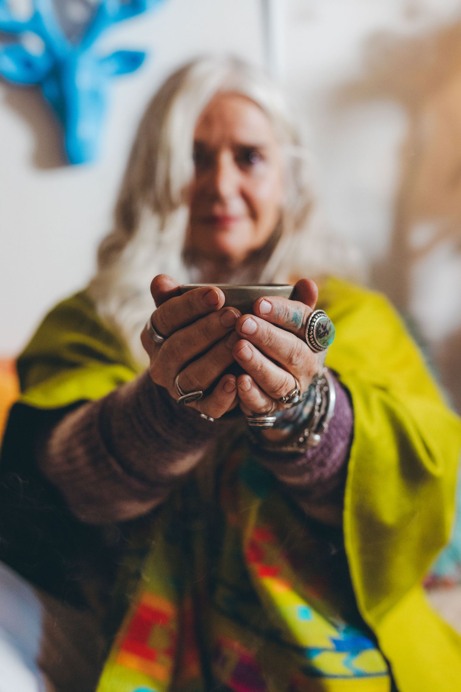 Hands holding a sacred object while wearing colorful bohemian style clothing.