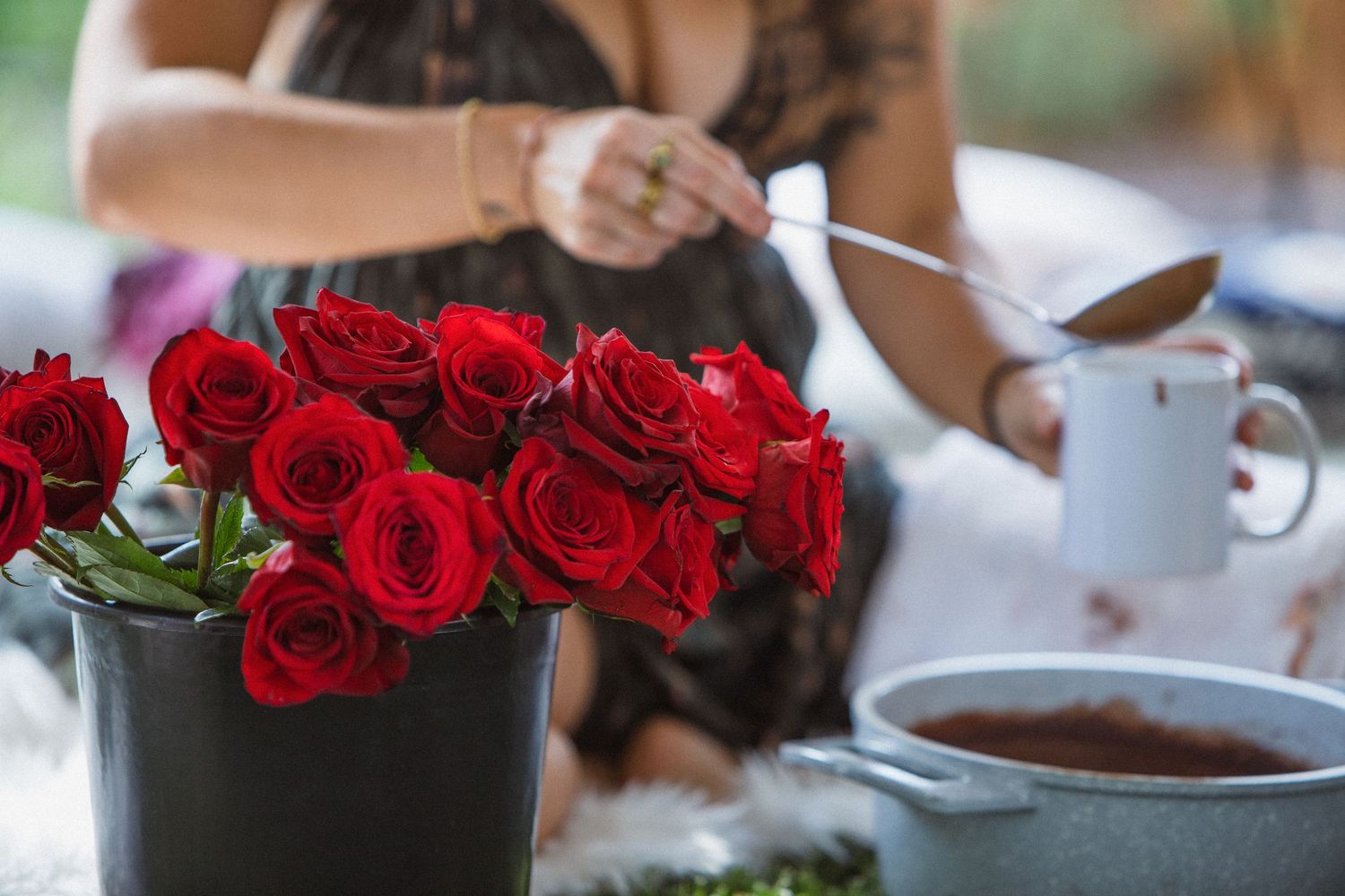 Red roses in elegant glass vases create an intimate and romantic tablescape at an indoor celebration.