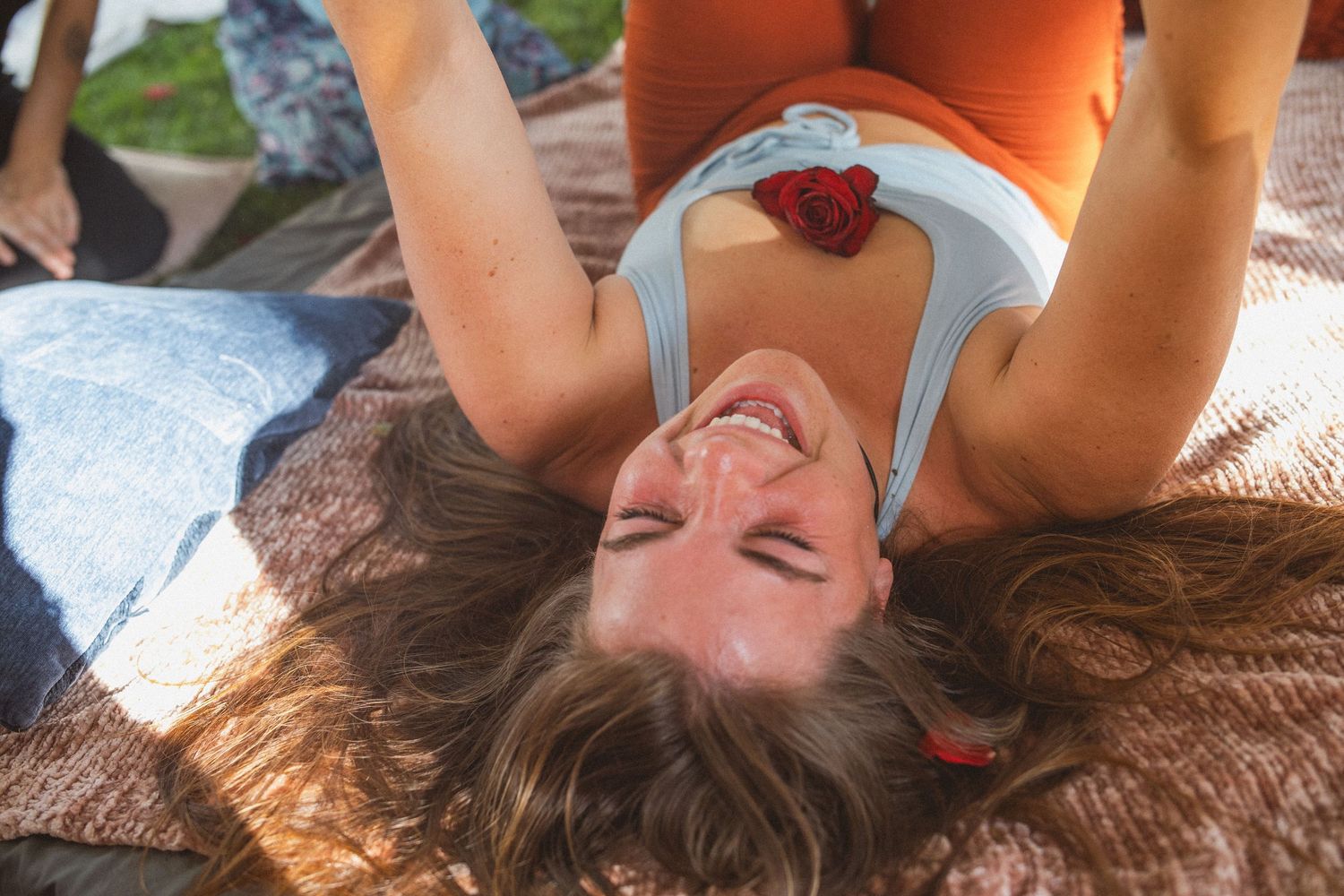 Guests laughing and enjoying themselves while laying on a blanket outdoors during a casual gathering.