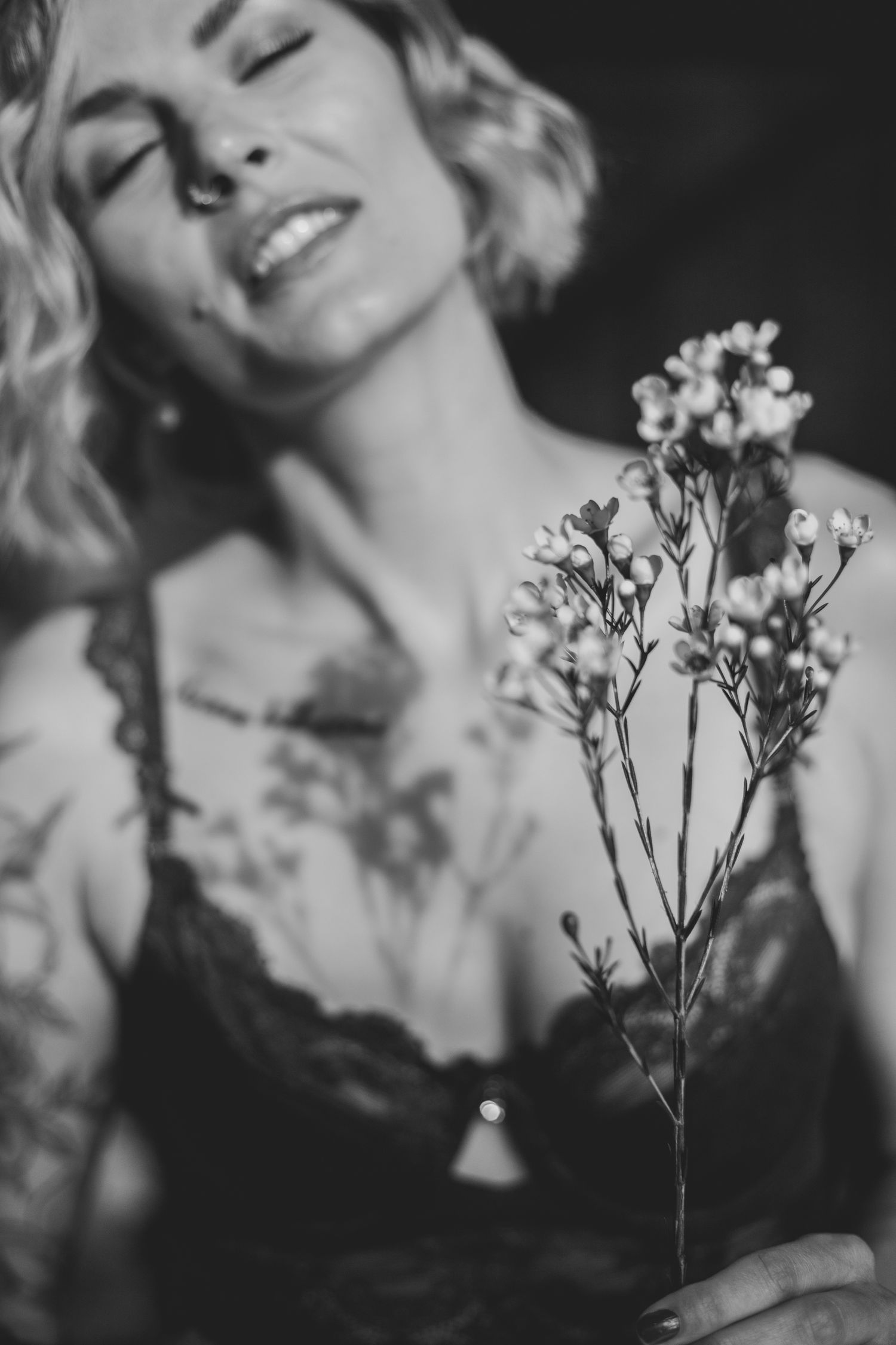 Black and white portrait with delicate wildflowers and dreamy lighting creating an artistic mood.