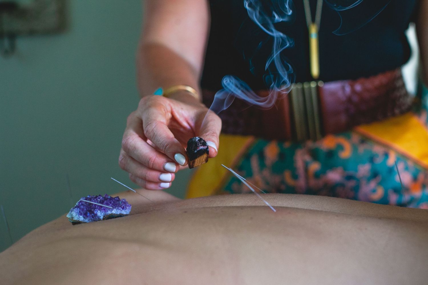 Therapeutic session showing burning sage and crystal healing treatment.