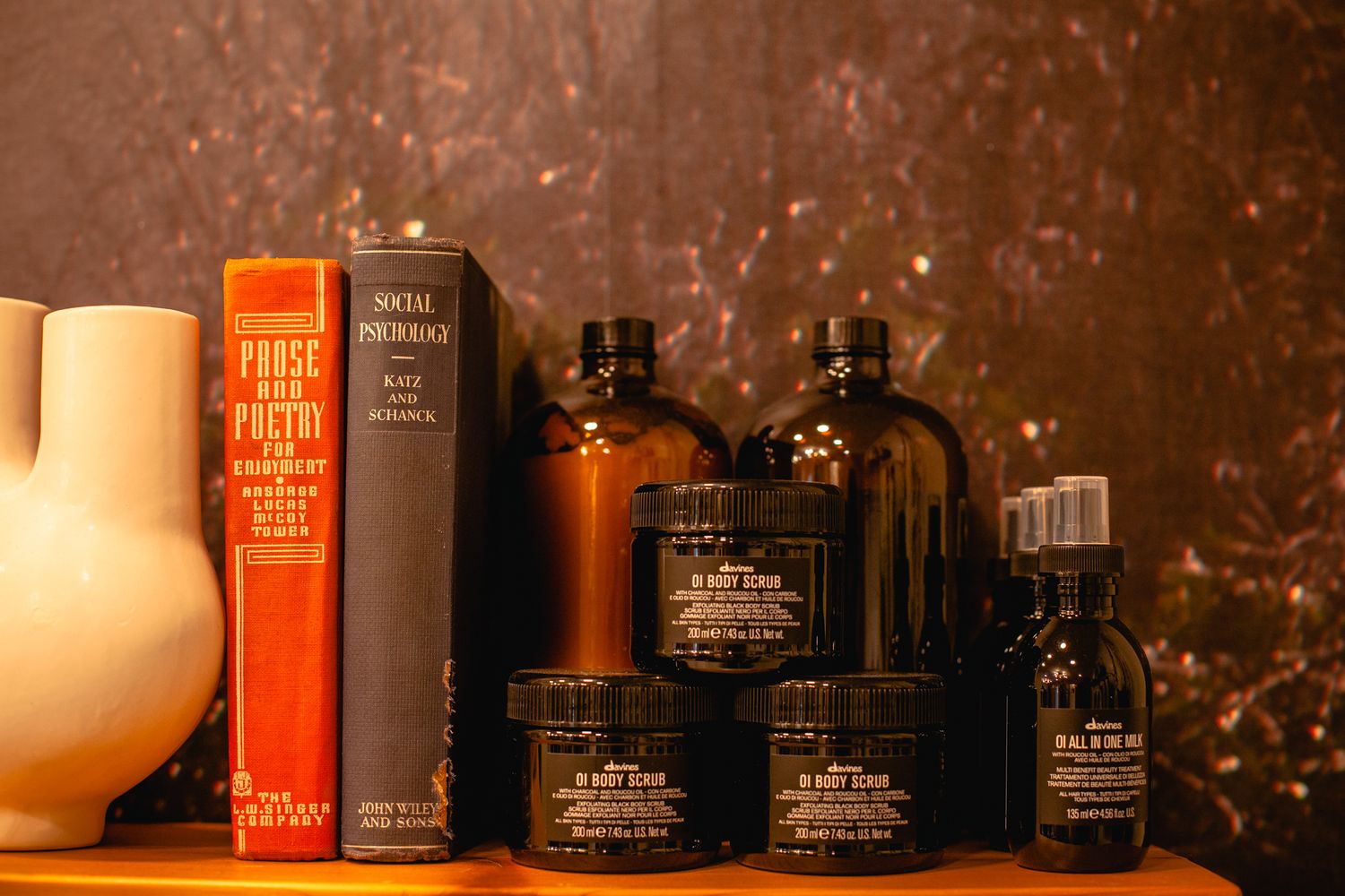 Collection of vintage amber bottles and books arranged on wooden shelf.