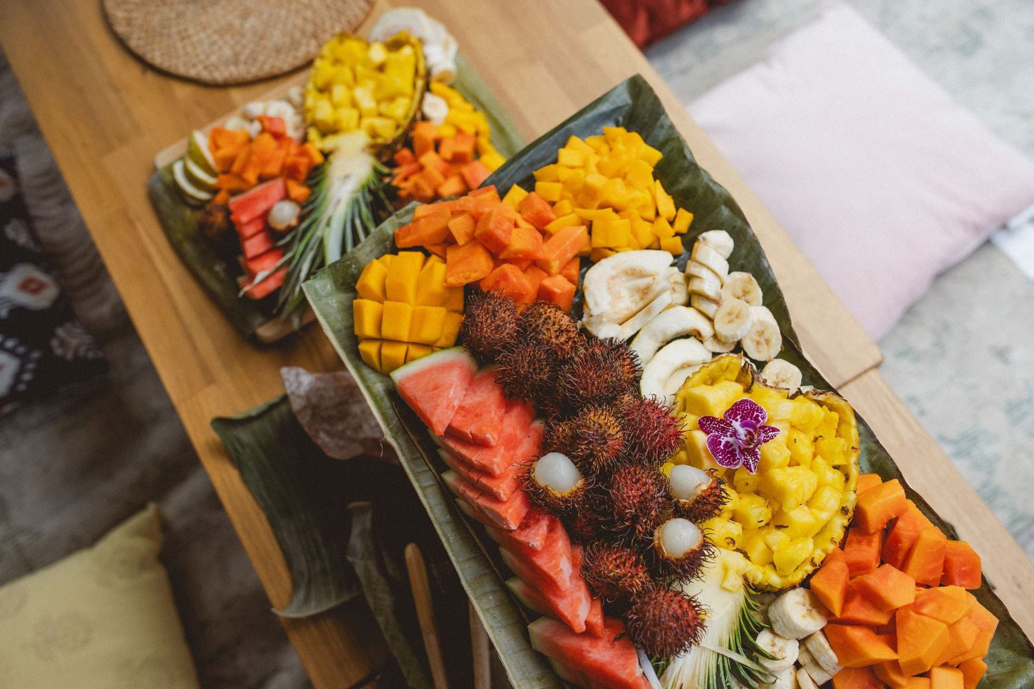 A vibrant charcuterie board displays colorful fruits, cheeses, meats and nuts arranged in rows on a wooden surface.