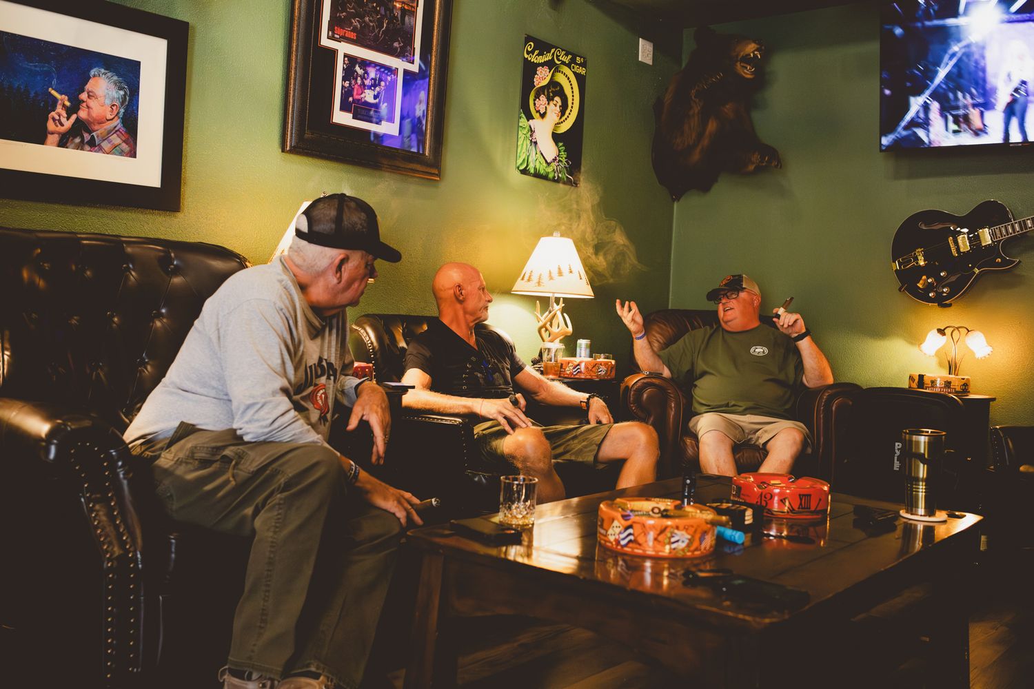 Group relaxing on leather couch in dimly lit room with pop culture artwork on walls.