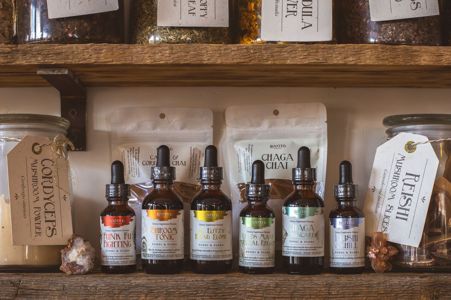 Display of natural tinctures and herbal remedies on wooden shelving with vintage labels.