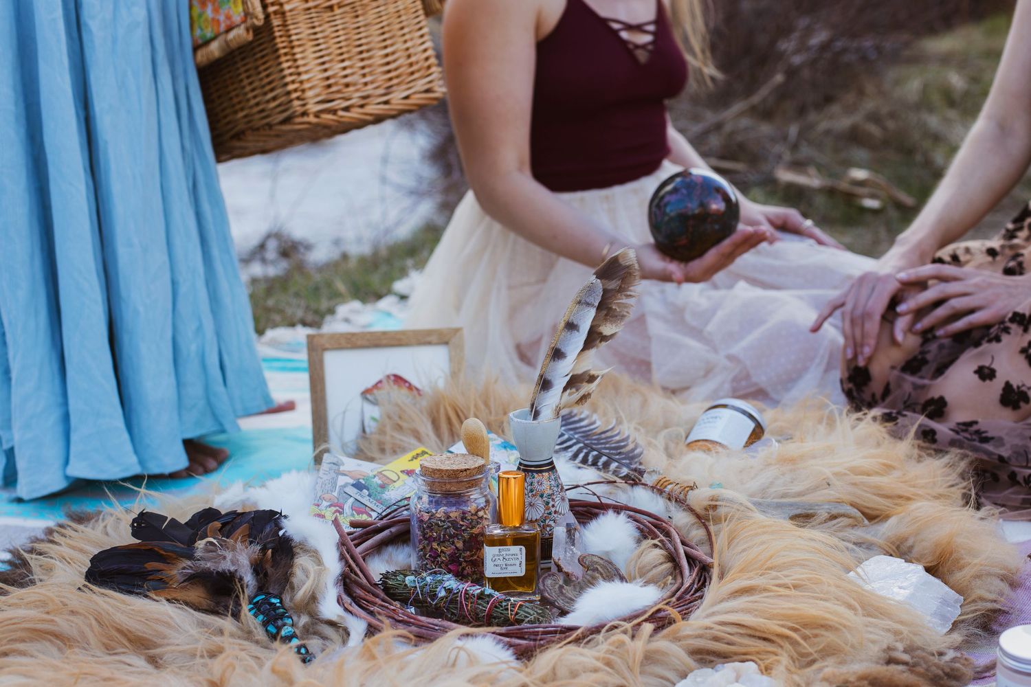 Boho style picnic setup with decorative elements and candles on fur blanket.