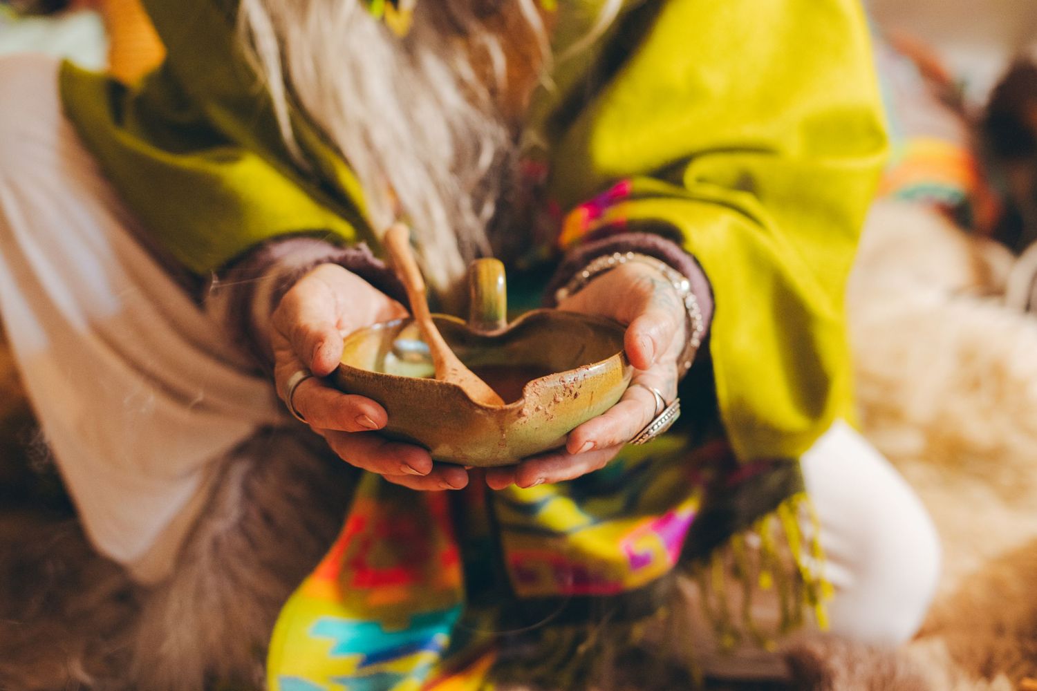 Hands holding healing herbs and natural ingredients in a colorful bohemian setting.