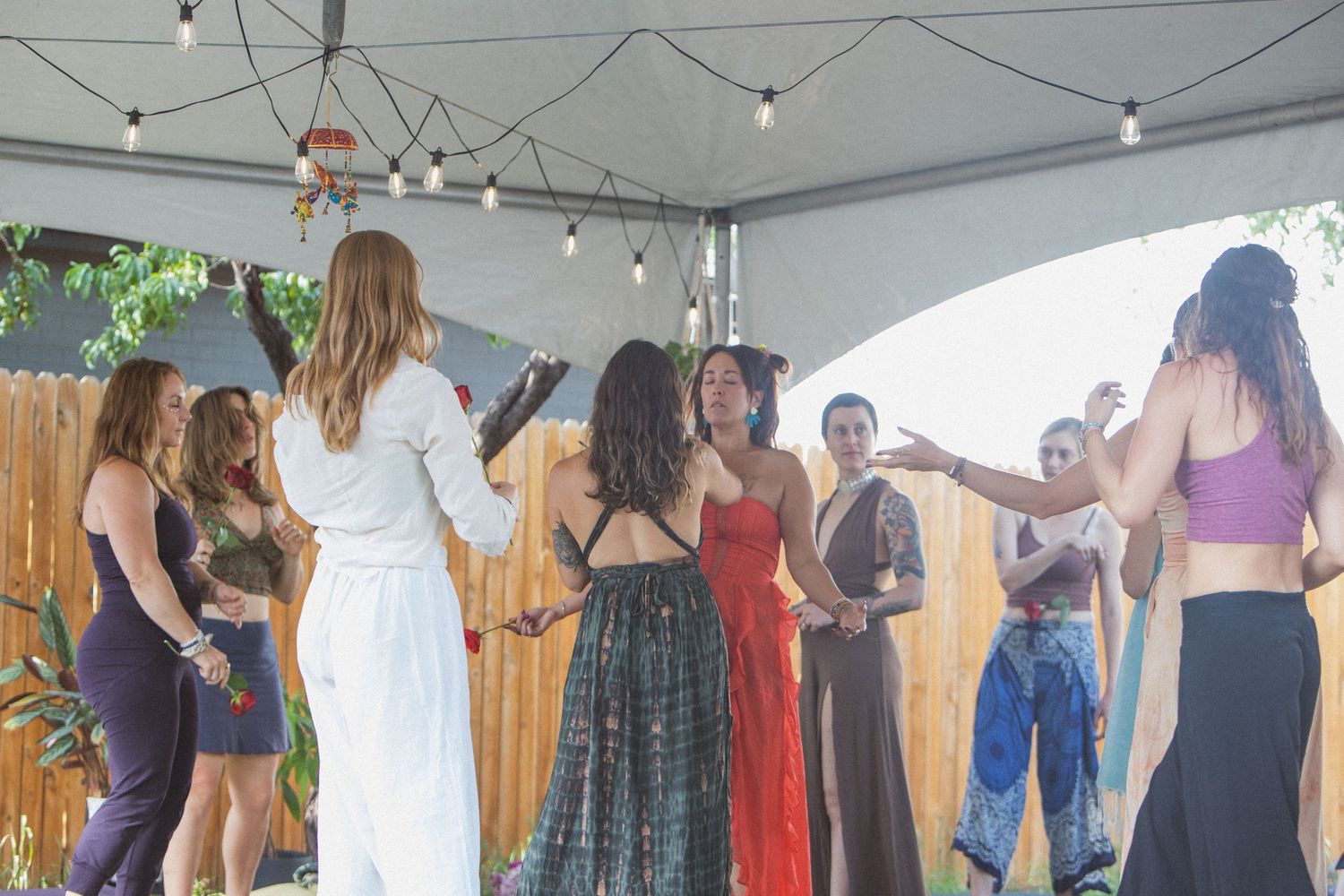 People participating in a group belly dance class in a bright studio space with large windows.