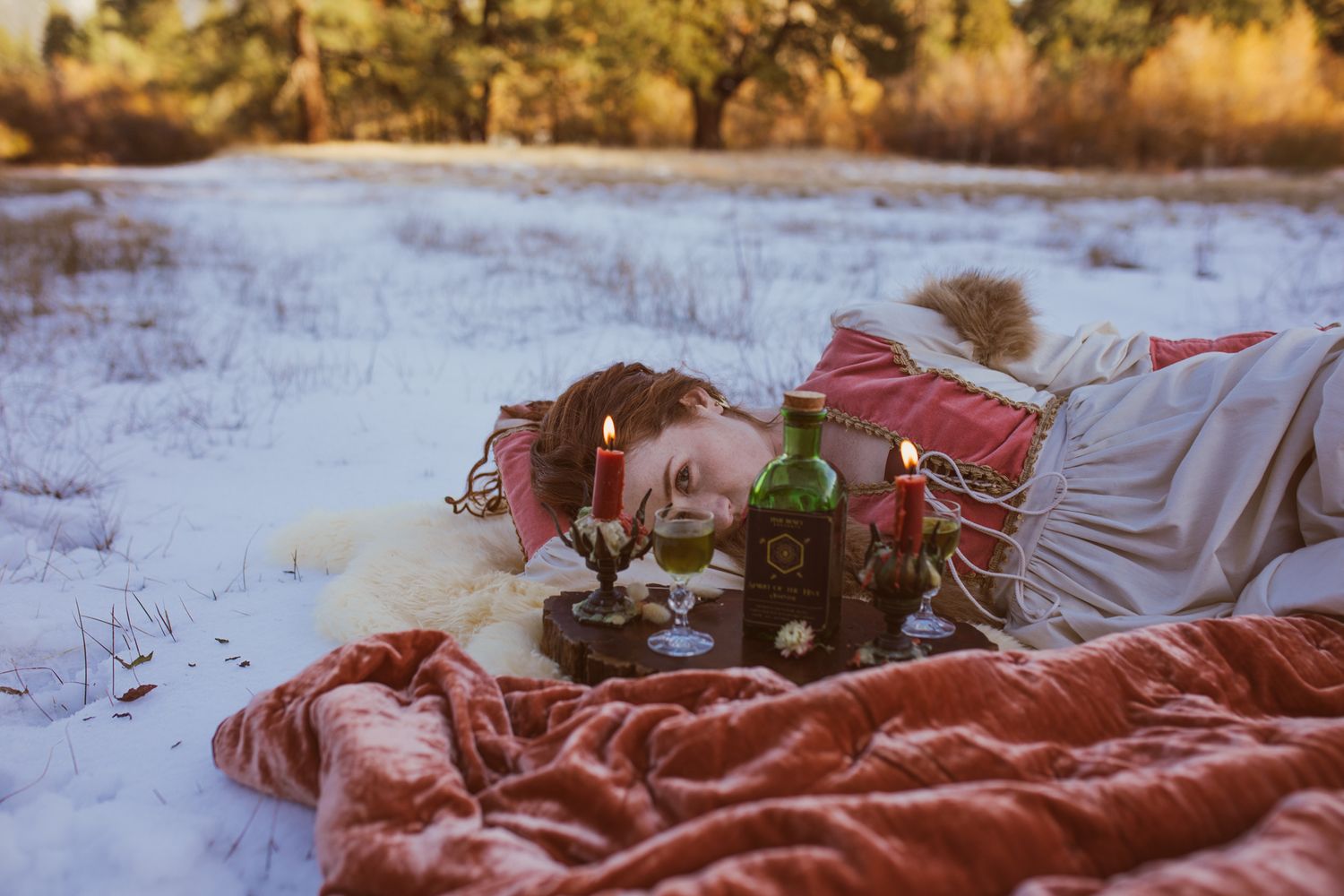 Winter scene with cozy blankets and vintage toy truck in snowy field at sunset.