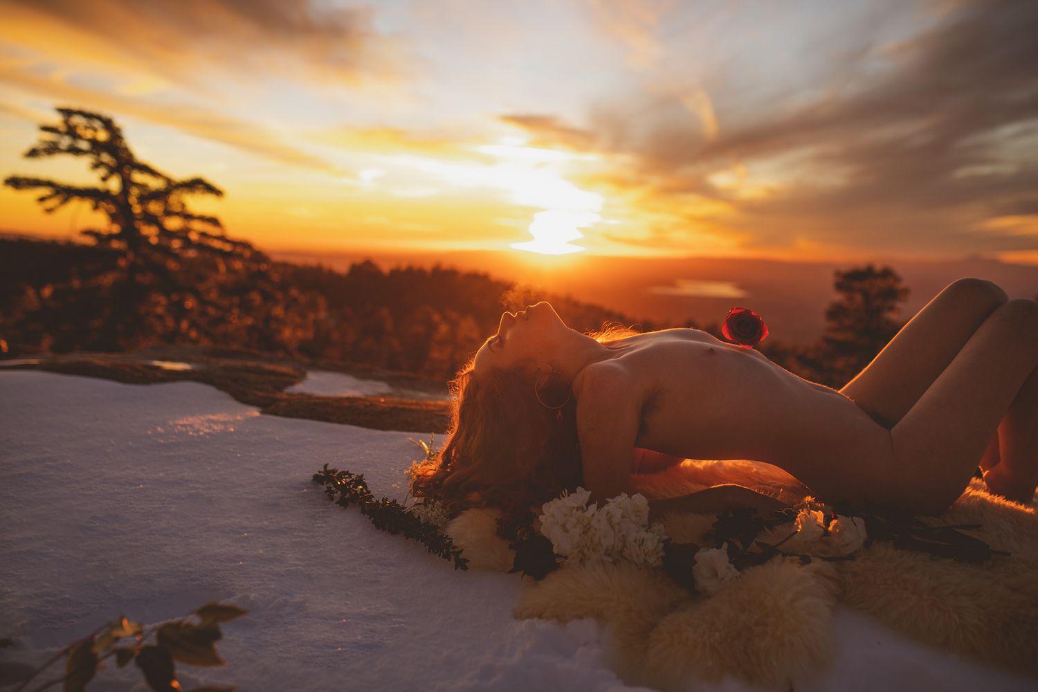 Silhouette figure reclining on snowy ground against dramatic sunset sky.