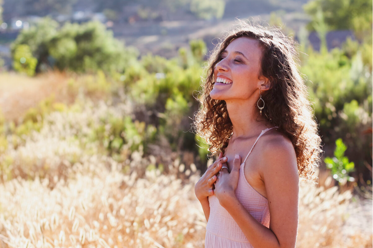 Candid portrait laughing in sunlit natural setting.