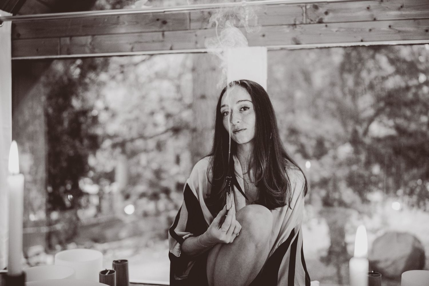 Candid black and white portrait in soft natural lighting with rustic background elements.
