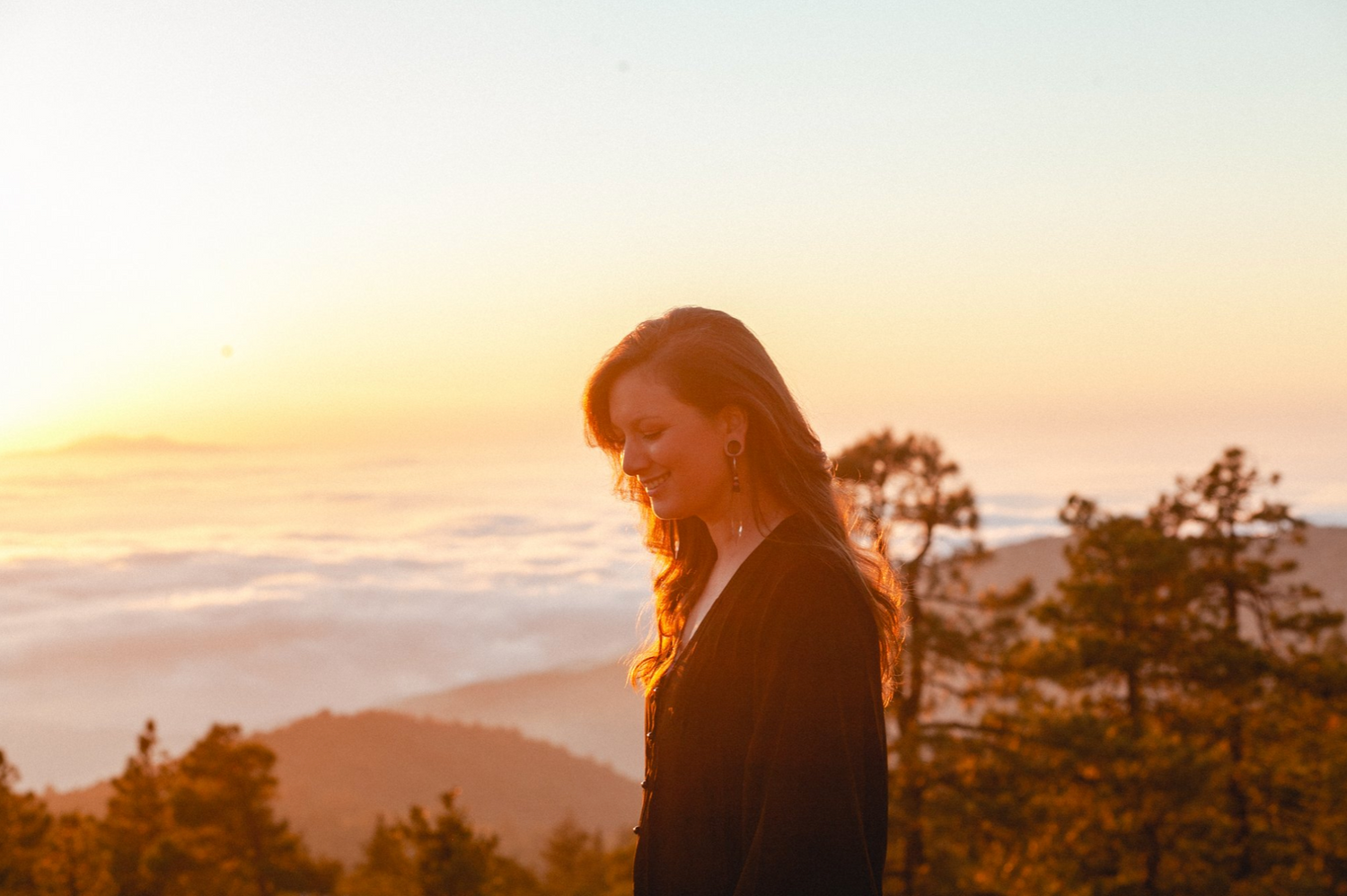 Silhouette at sunset with mountains and fog in background.