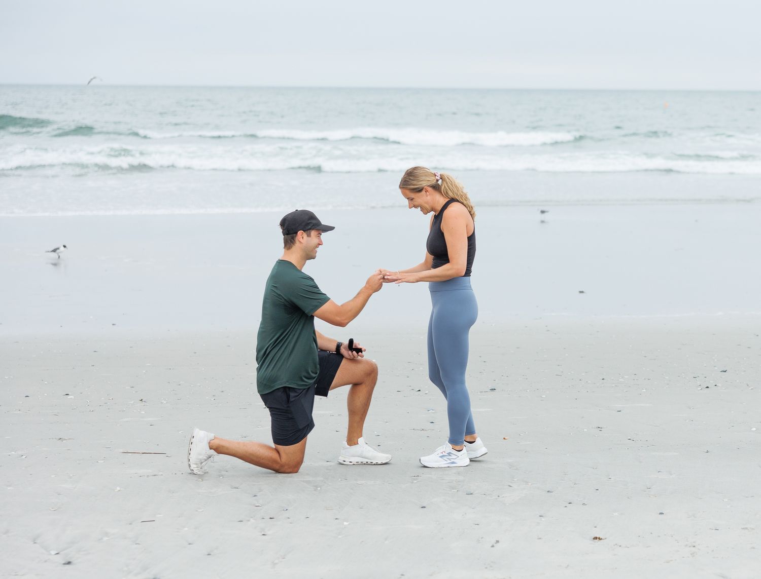A romantic beach proposal sequence shows someone kneeling on one knee in the sand to ask an important question.