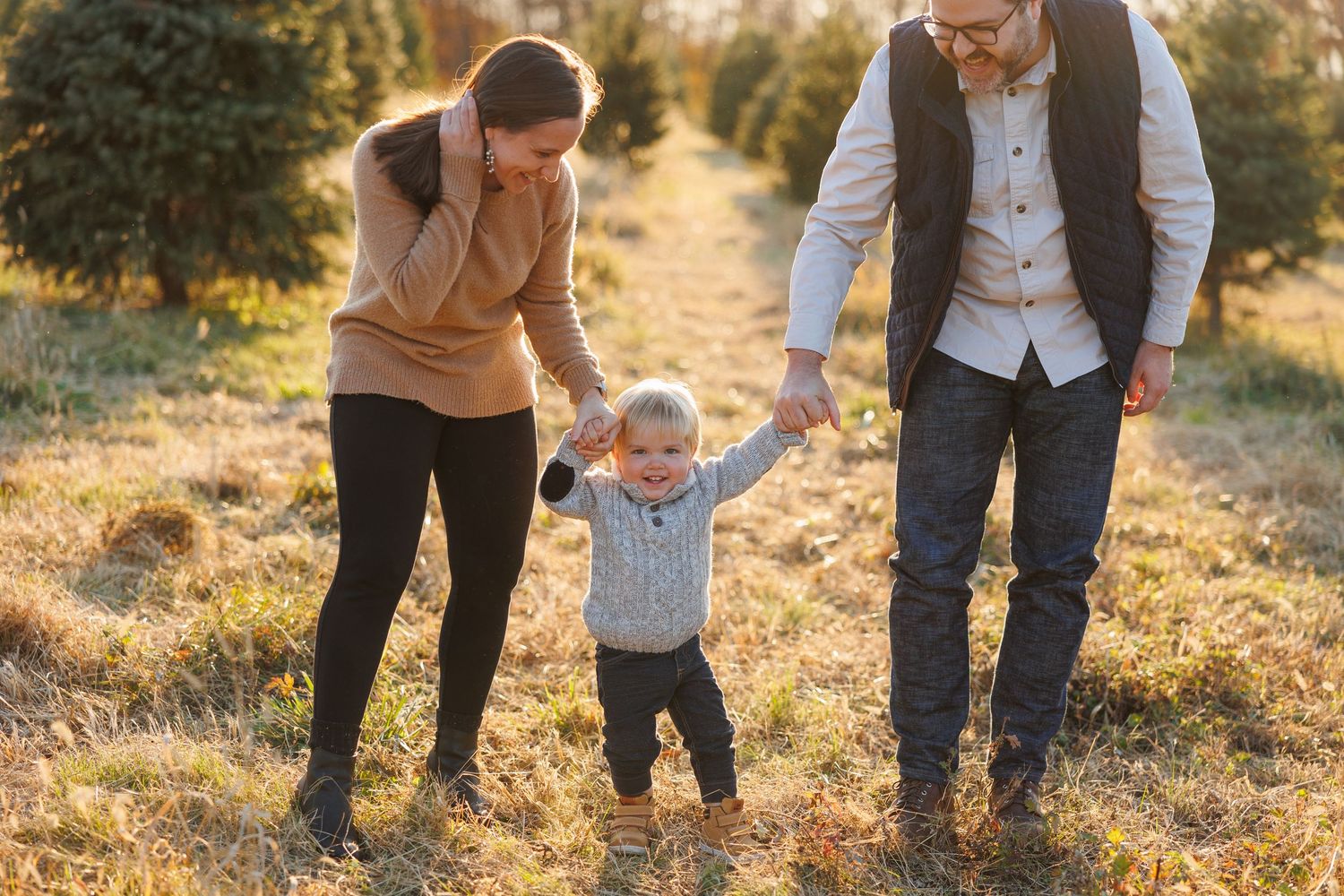 A family walks together through a sunlit meadow during golden hour, creating a warm and intimate outdoor scene.