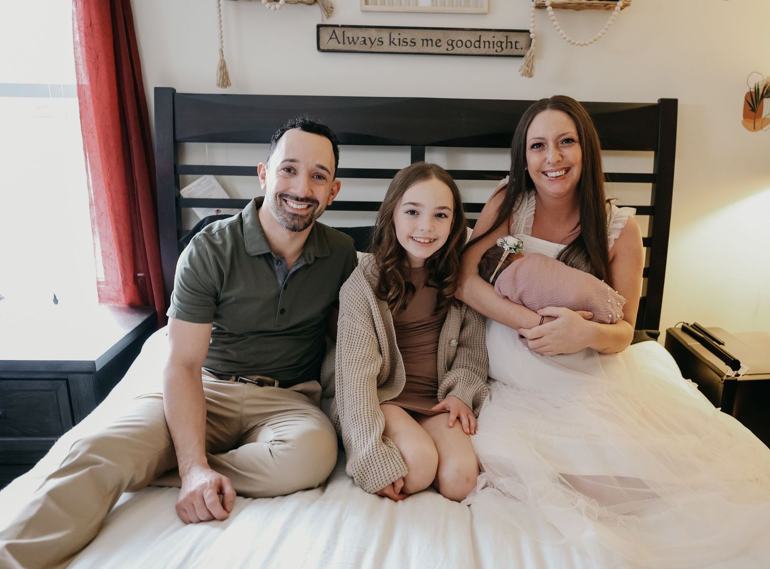 Happy family relaxing together on bed with newborn baby.