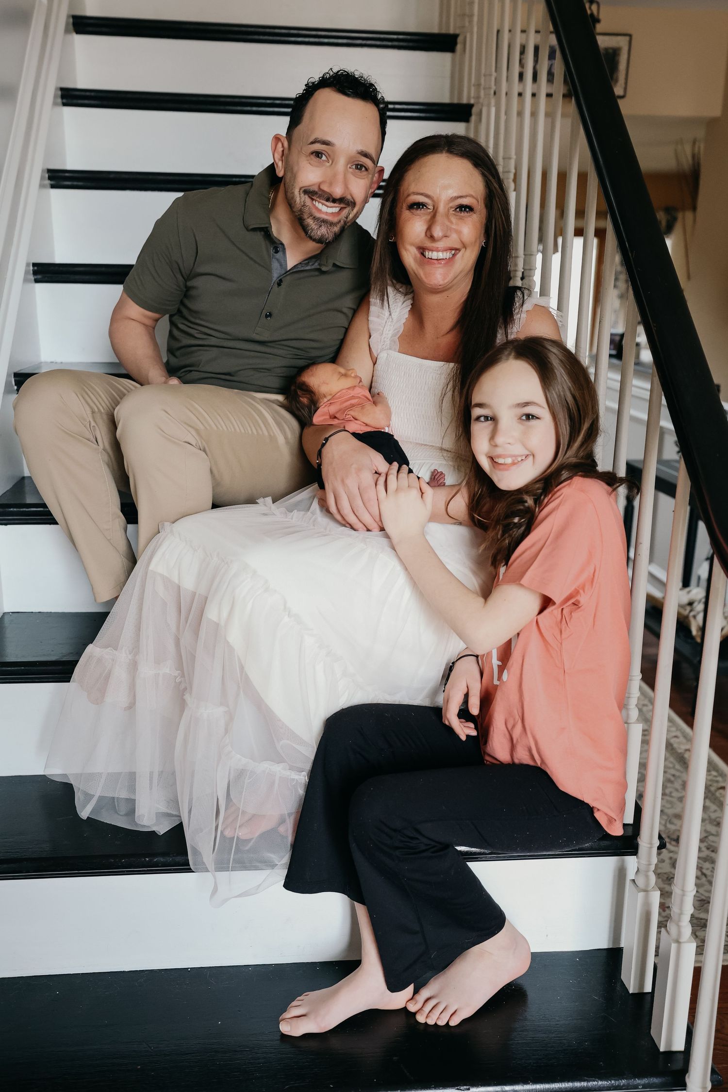 Family sitting on black and white stairs sharing intimate moment together.