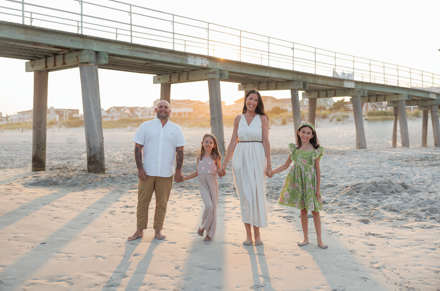 Group walking together on sandy beach at sunset while holding hands and enjoying a peaceful moment.