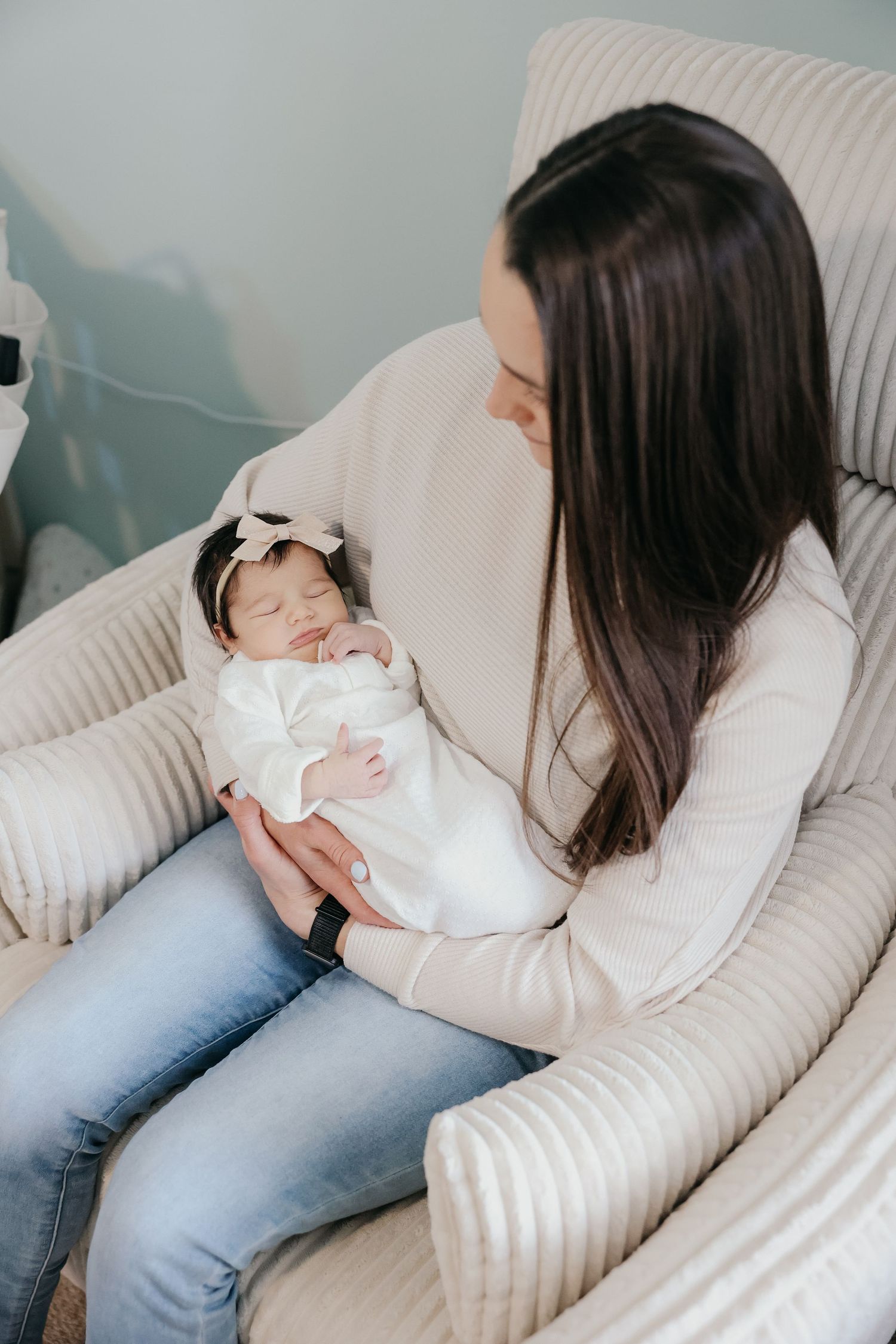 Close up of mother and sleeping baby in white chair.