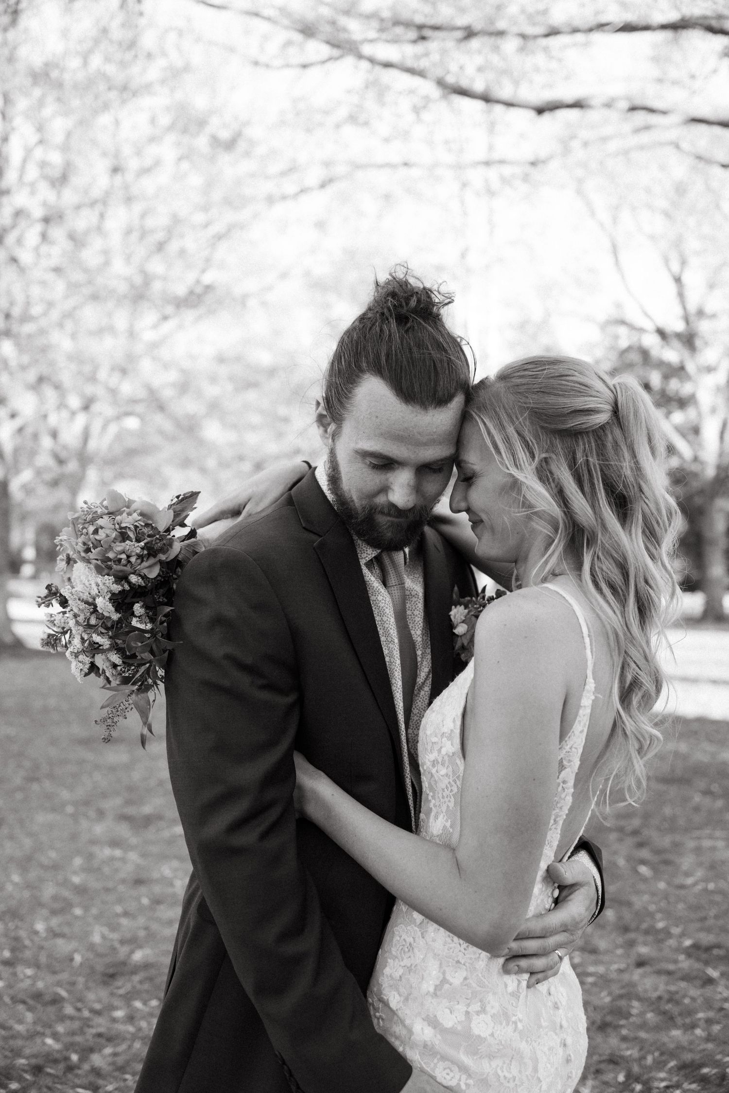 Groom embraces his bride holding a bouquet in a timeless black and white wedding portrait at Lee Hall in Virginia.